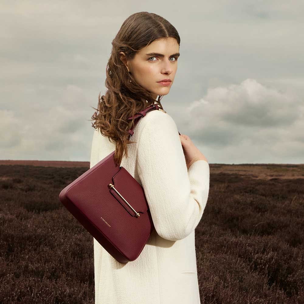 A woman in a white dress holding a red purse