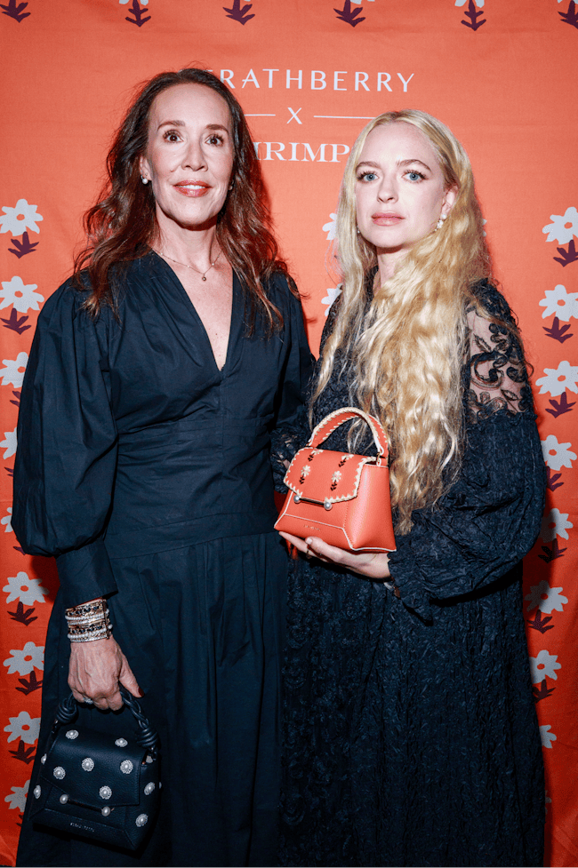 Two women standing next to each other holding purses