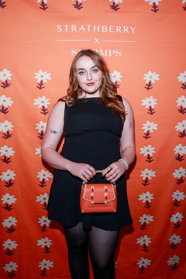 A woman in a black dress holding a red purse