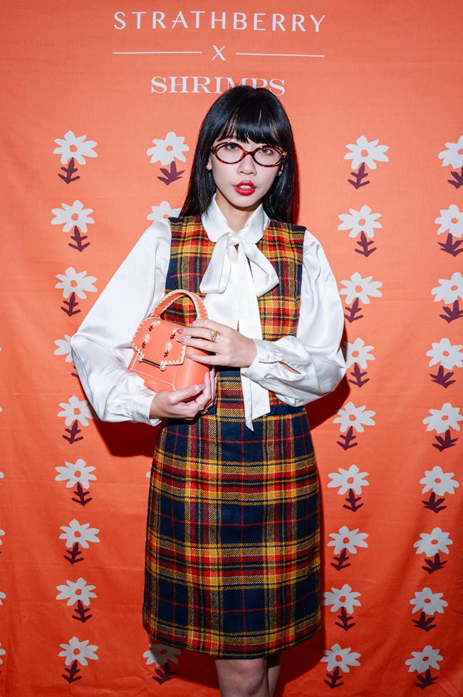 A woman in a plaid dress holding a cookie