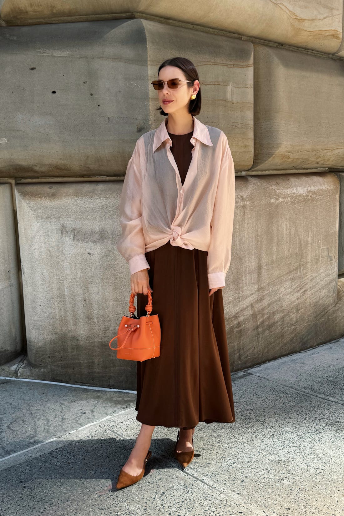 A woman standing on a sidewalk holding a purse