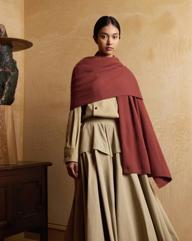 A woman standing in a room with a red shawl