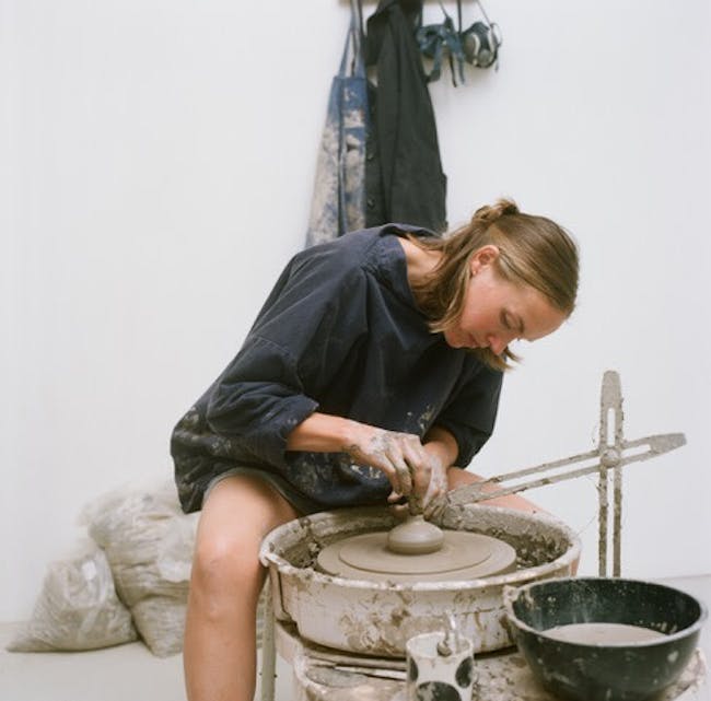 A woman is making a pot on a wheel