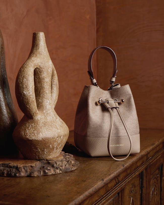 A purse sitting on top of a wooden table next to a vase