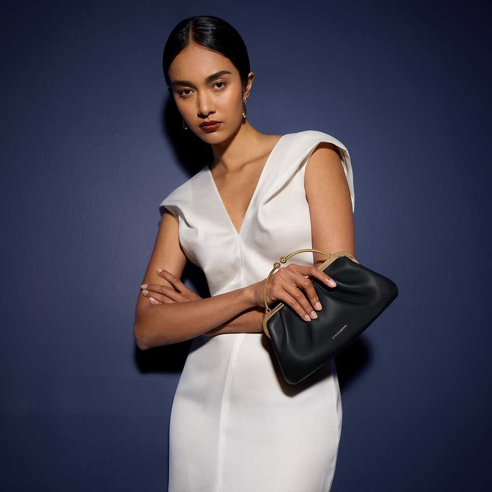 A woman in a white dress holding a black purse