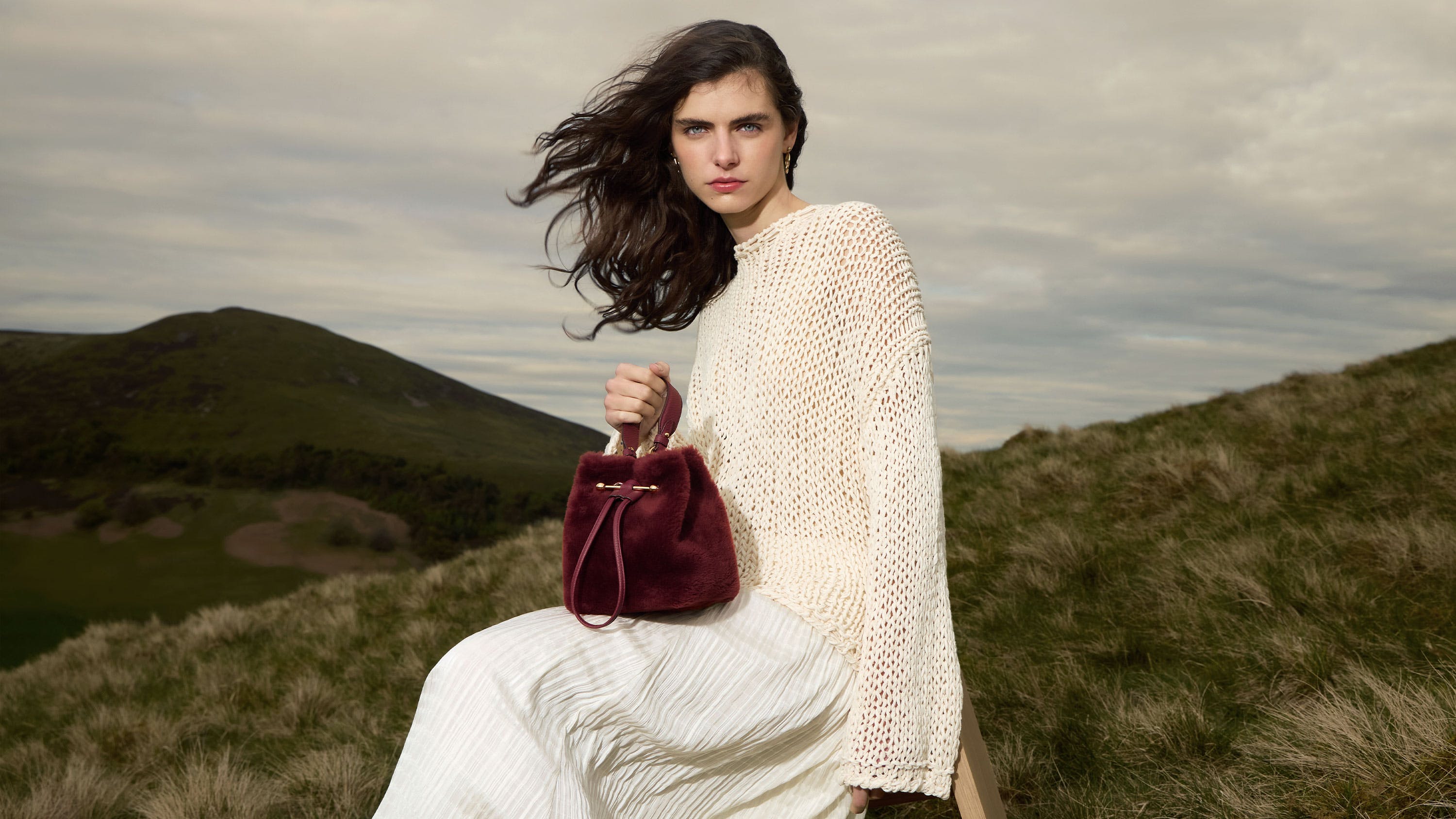 A woman in a white dress holding a red purse