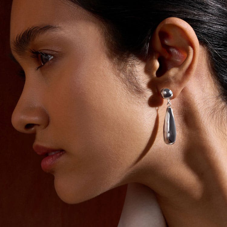 A close up of a person wearing silver earrings