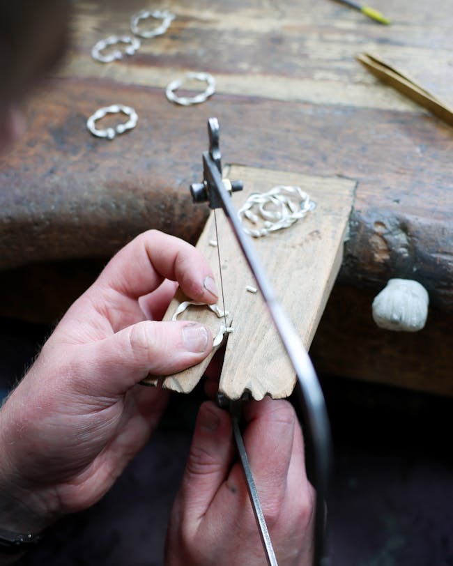 A person using a pair of scissors to cut a piece of wood