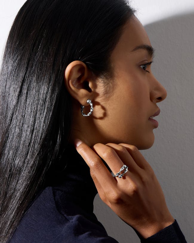 A woman wearing a pair of silver hoop earrings