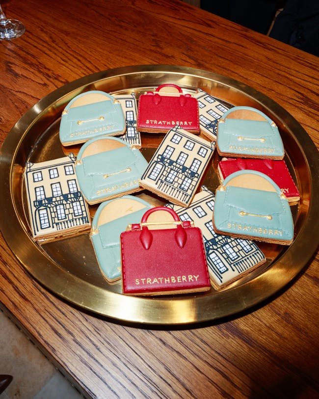 A plate of cookies decorated like purses on a table