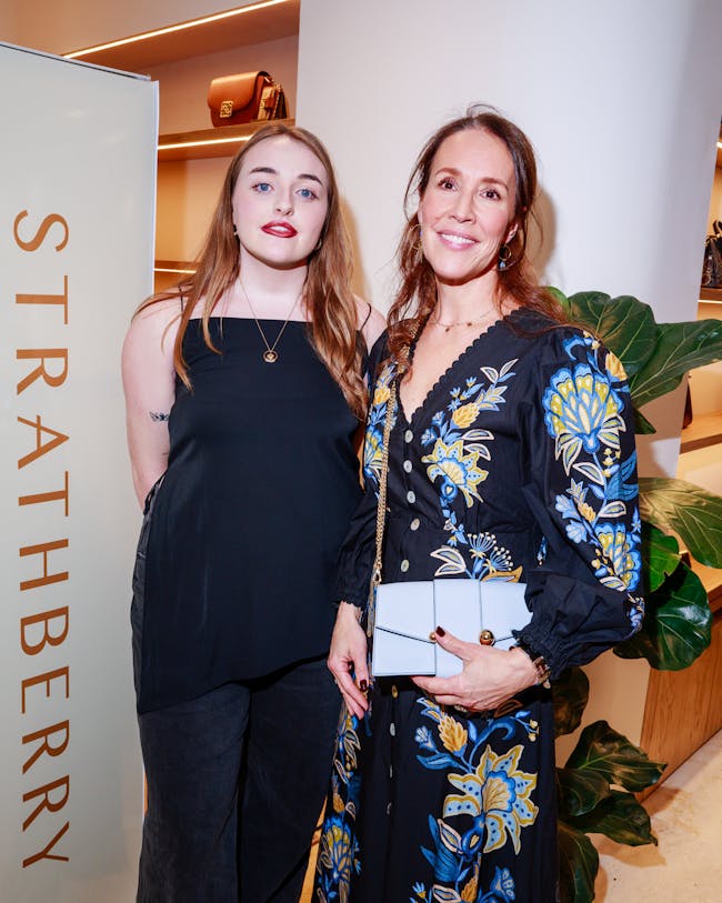 Two women standing next to each other in front of a sign