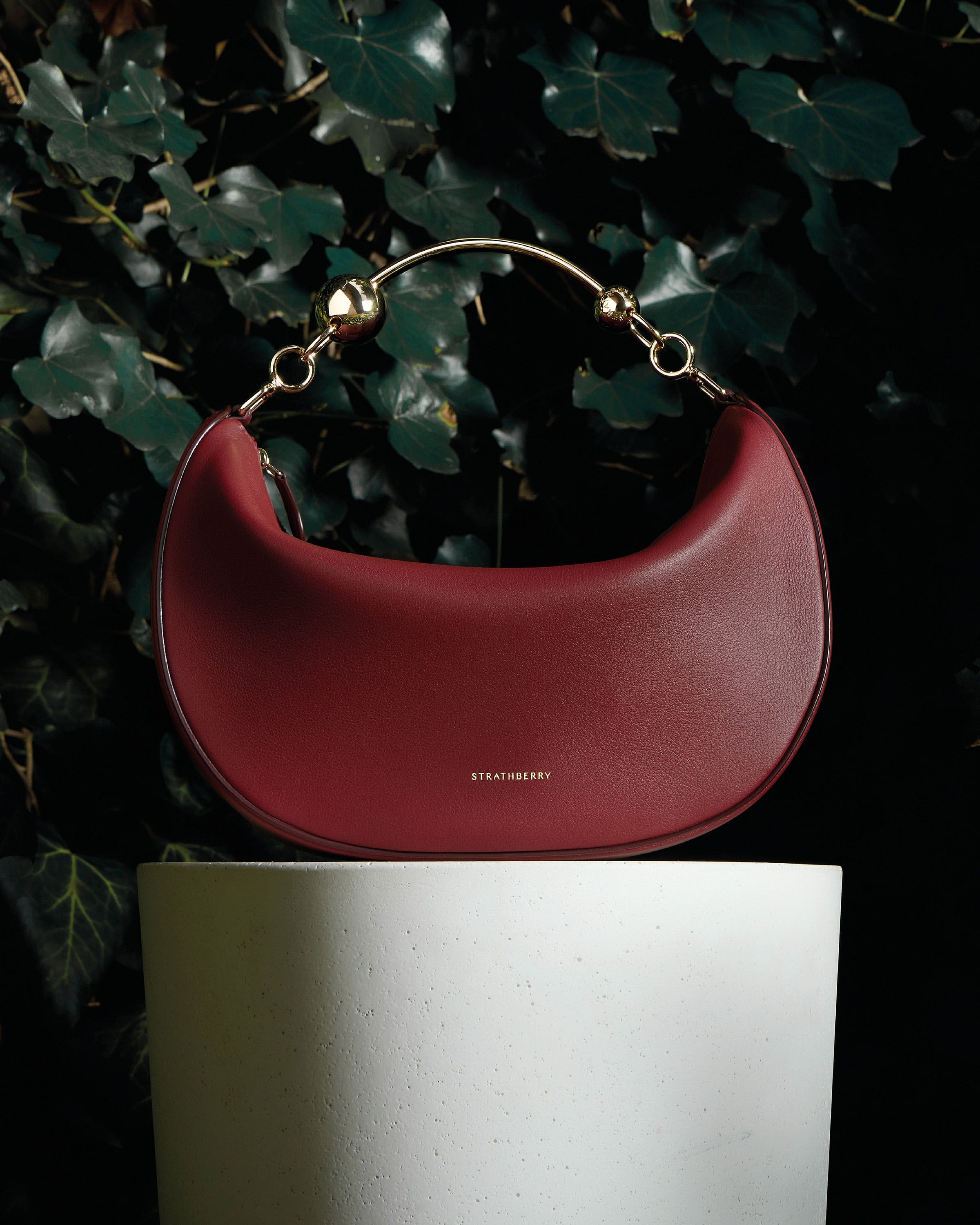 A red purse sitting on top of a white pedestal