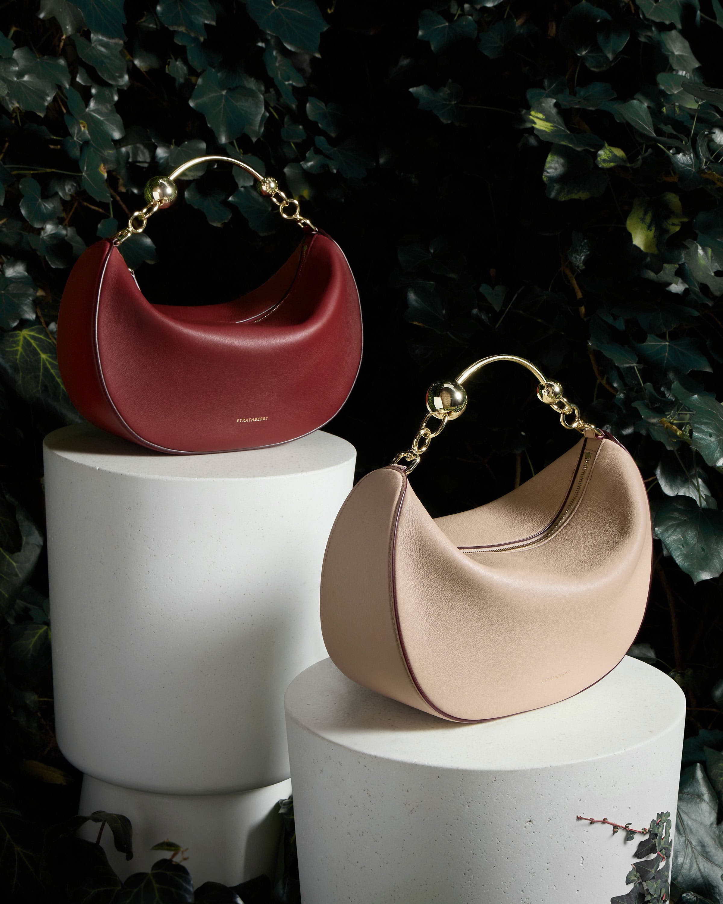 A couple of purses sitting on top of a white pedestal