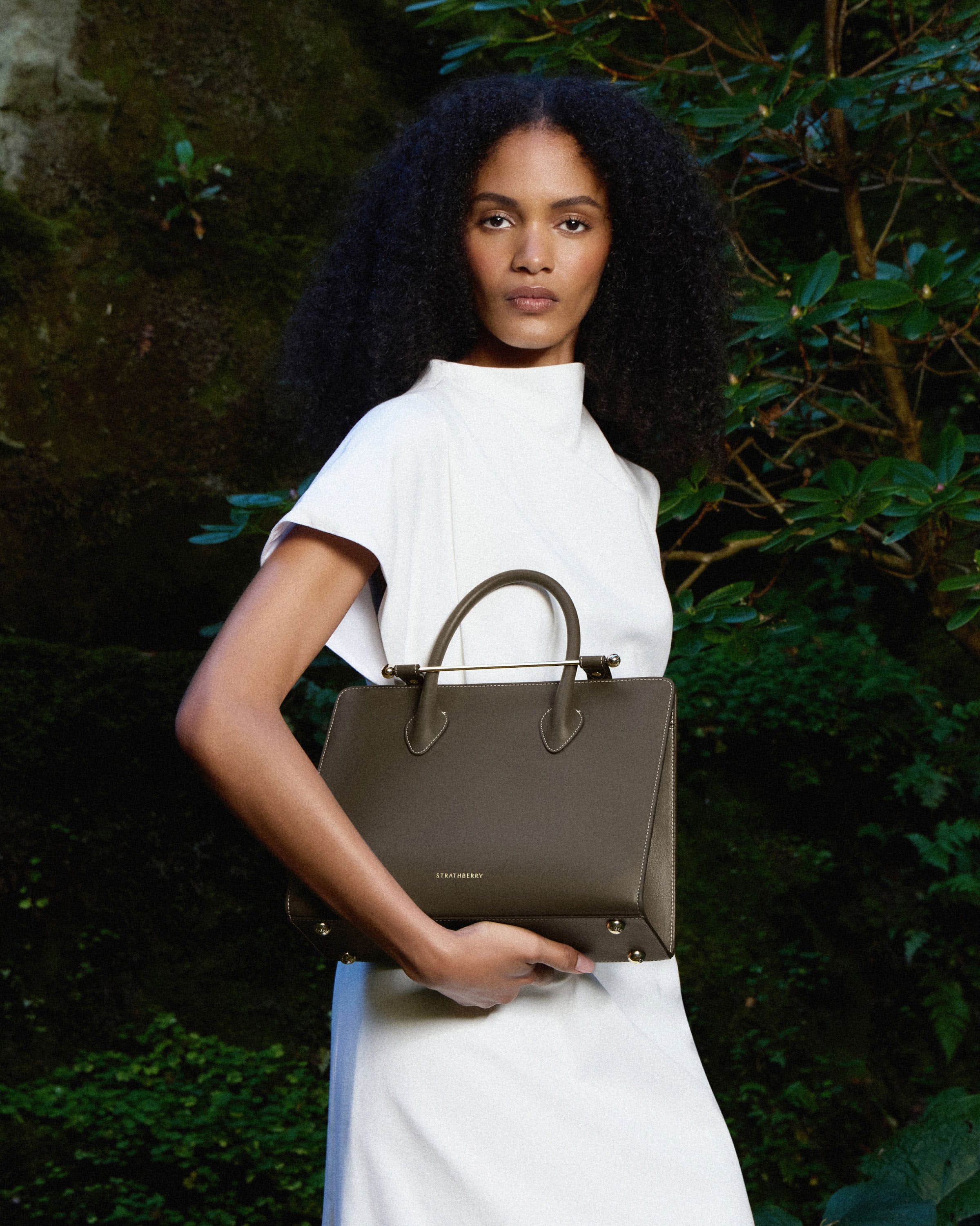 A woman in a white dress holding a brown purse