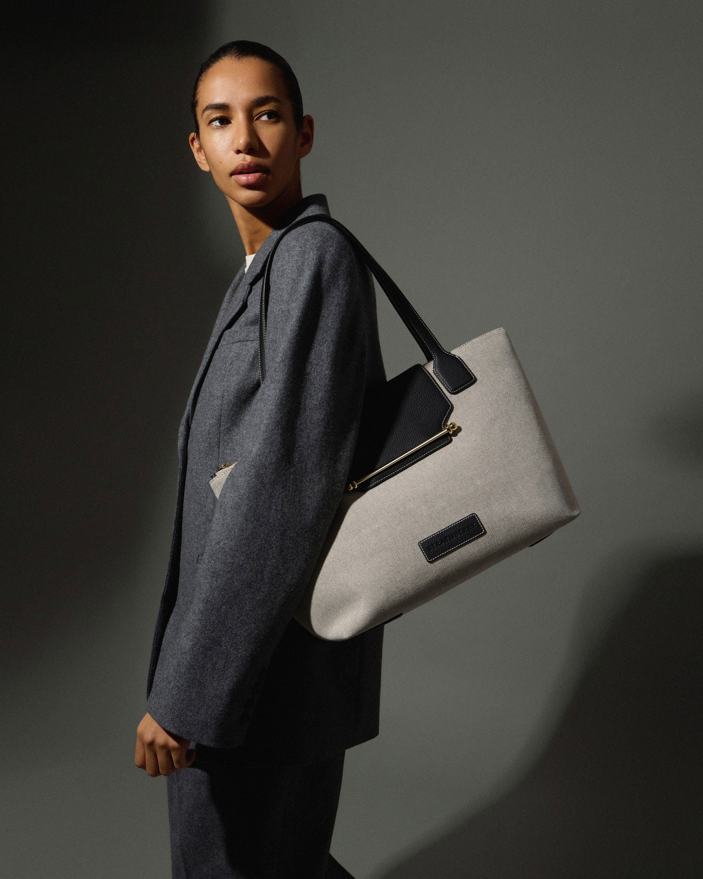 A woman in a suit carrying a white bag