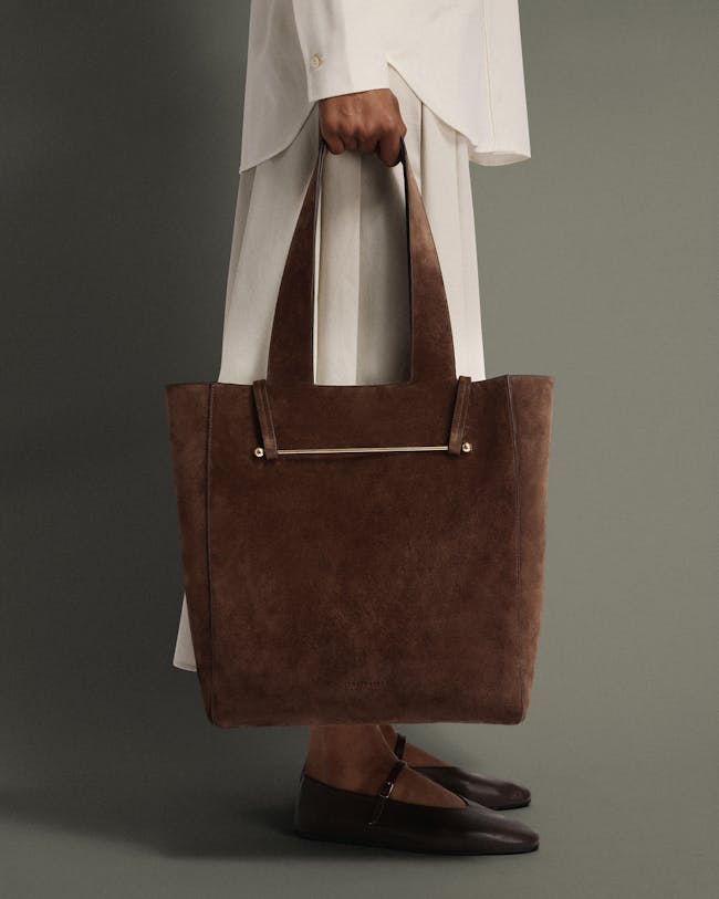 A woman holding a brown suede tote bag