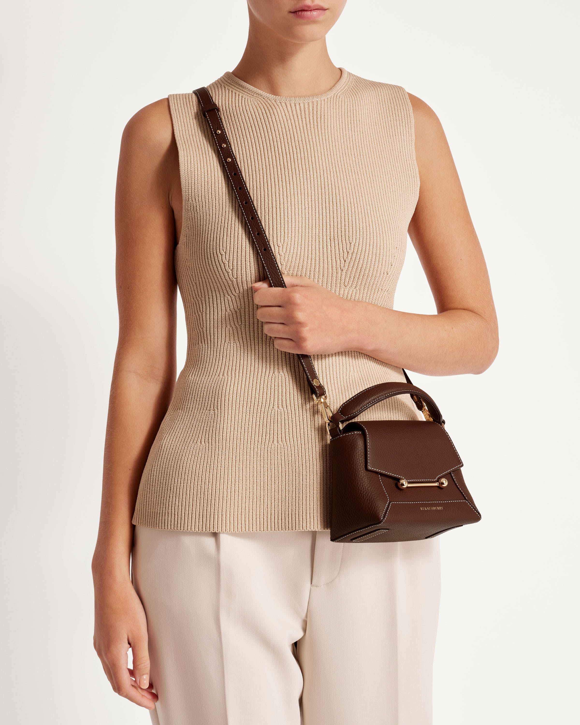 A woman is holding a brown purse