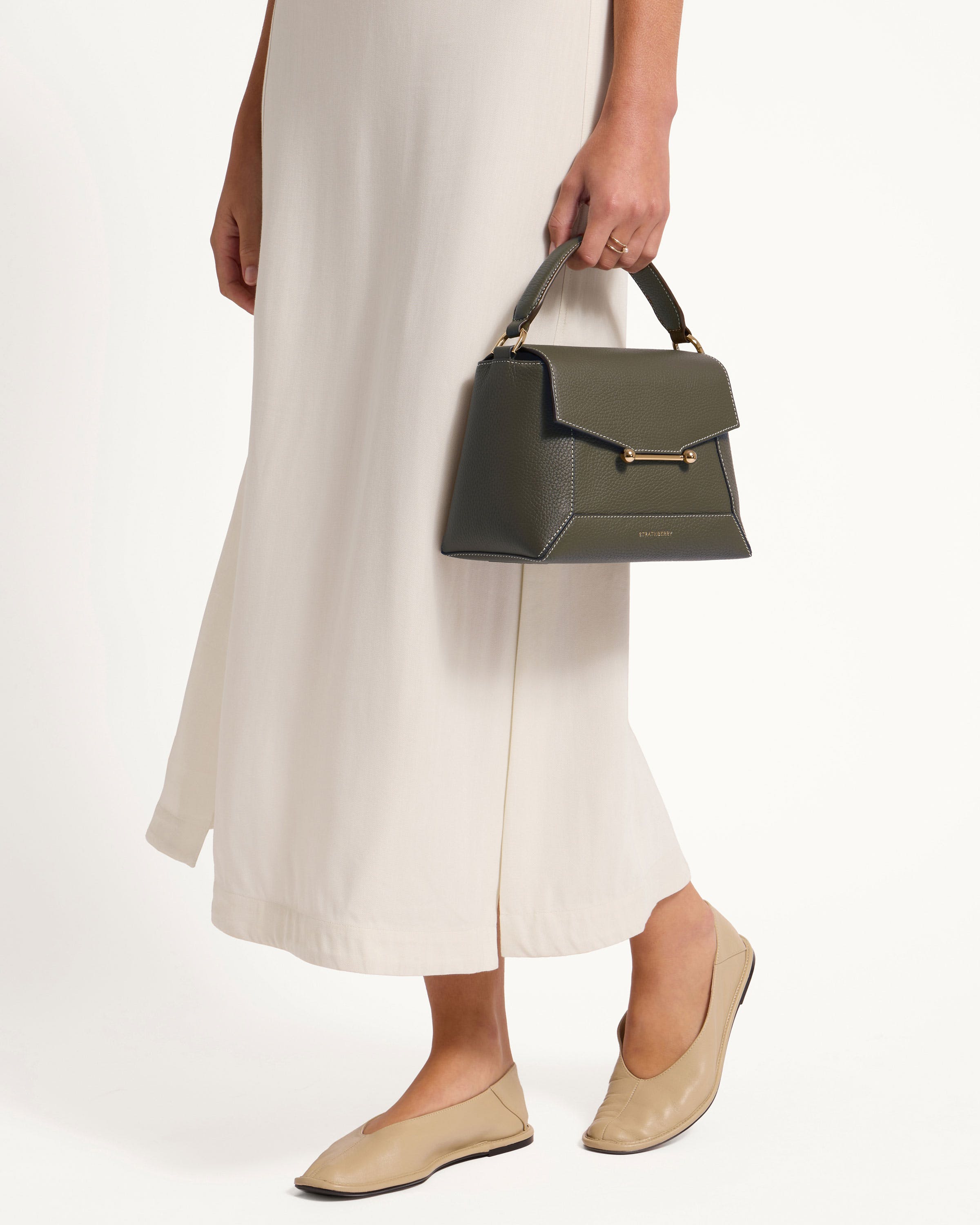 A woman in a white dress holding a black handbag