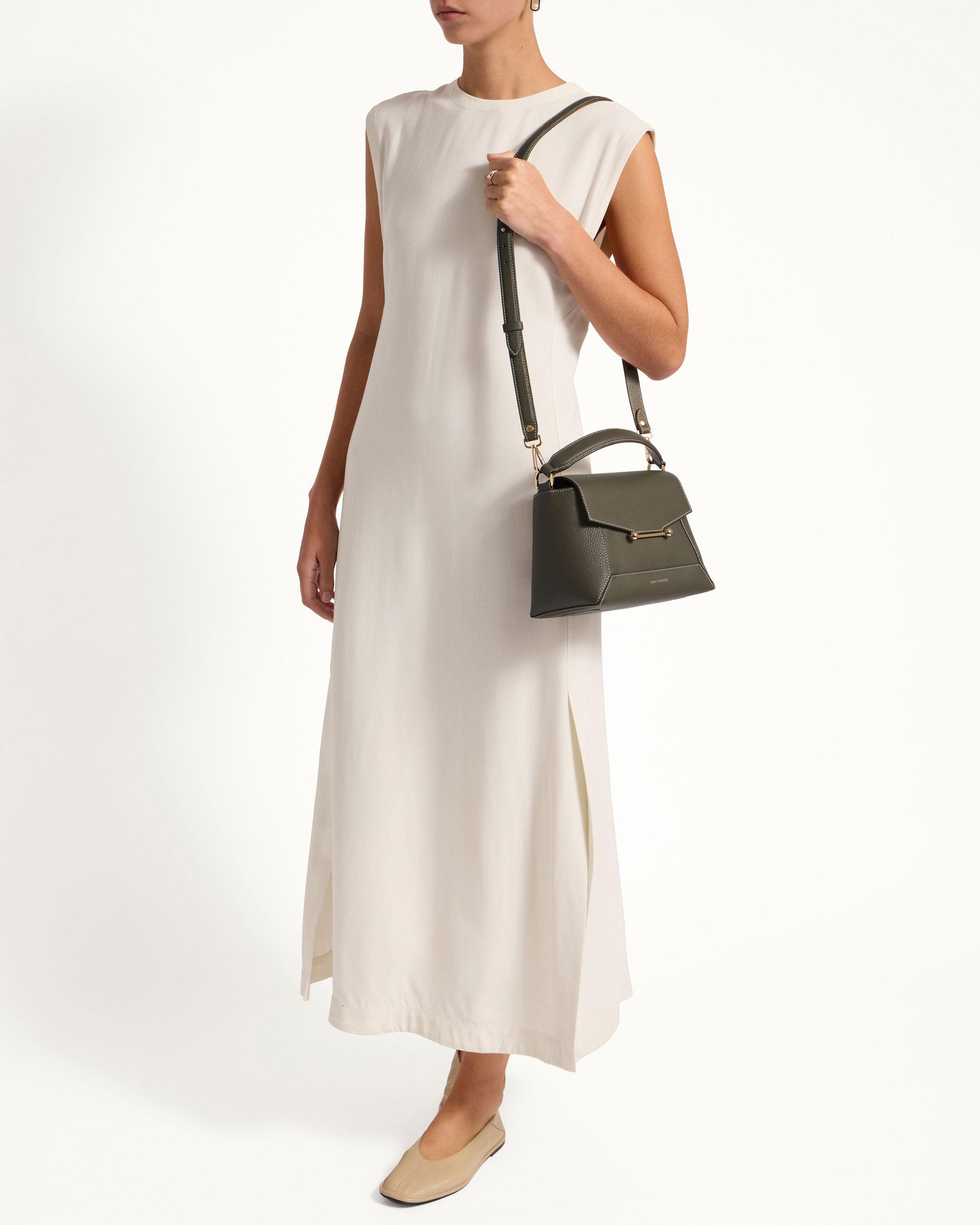 A woman in a white dress holding a black handbag