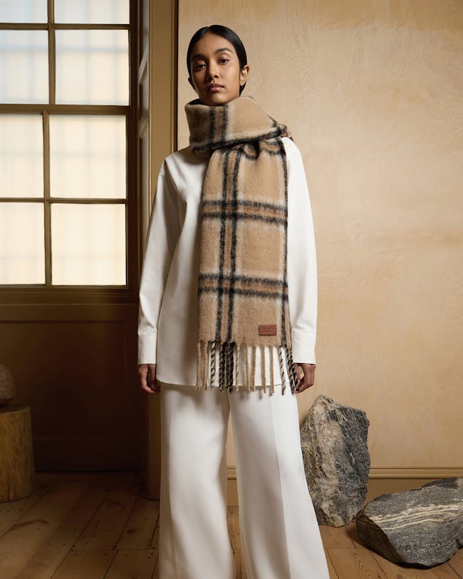 A woman in white pants and a plaid scarf