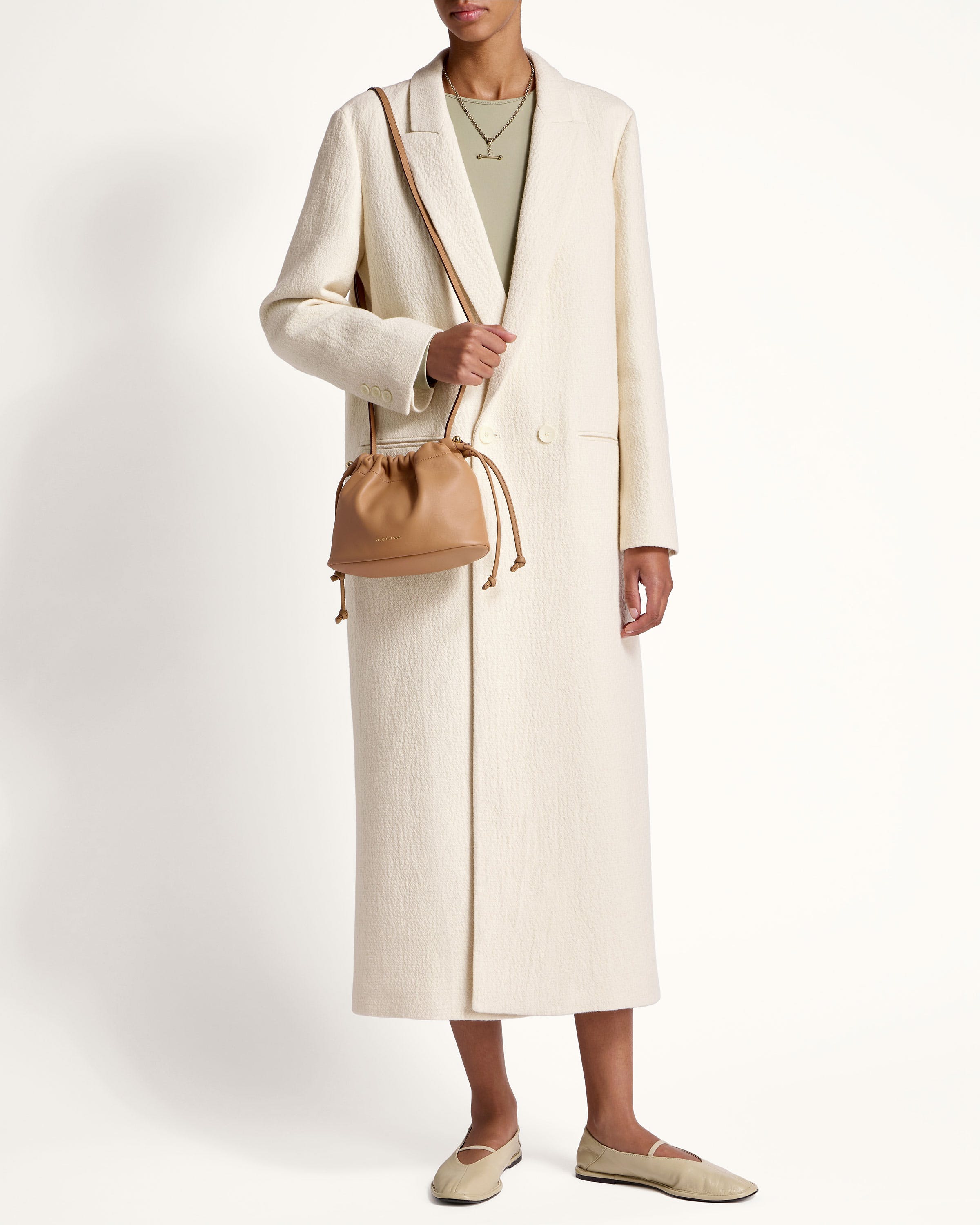 A woman in a white coat holding a brown bag