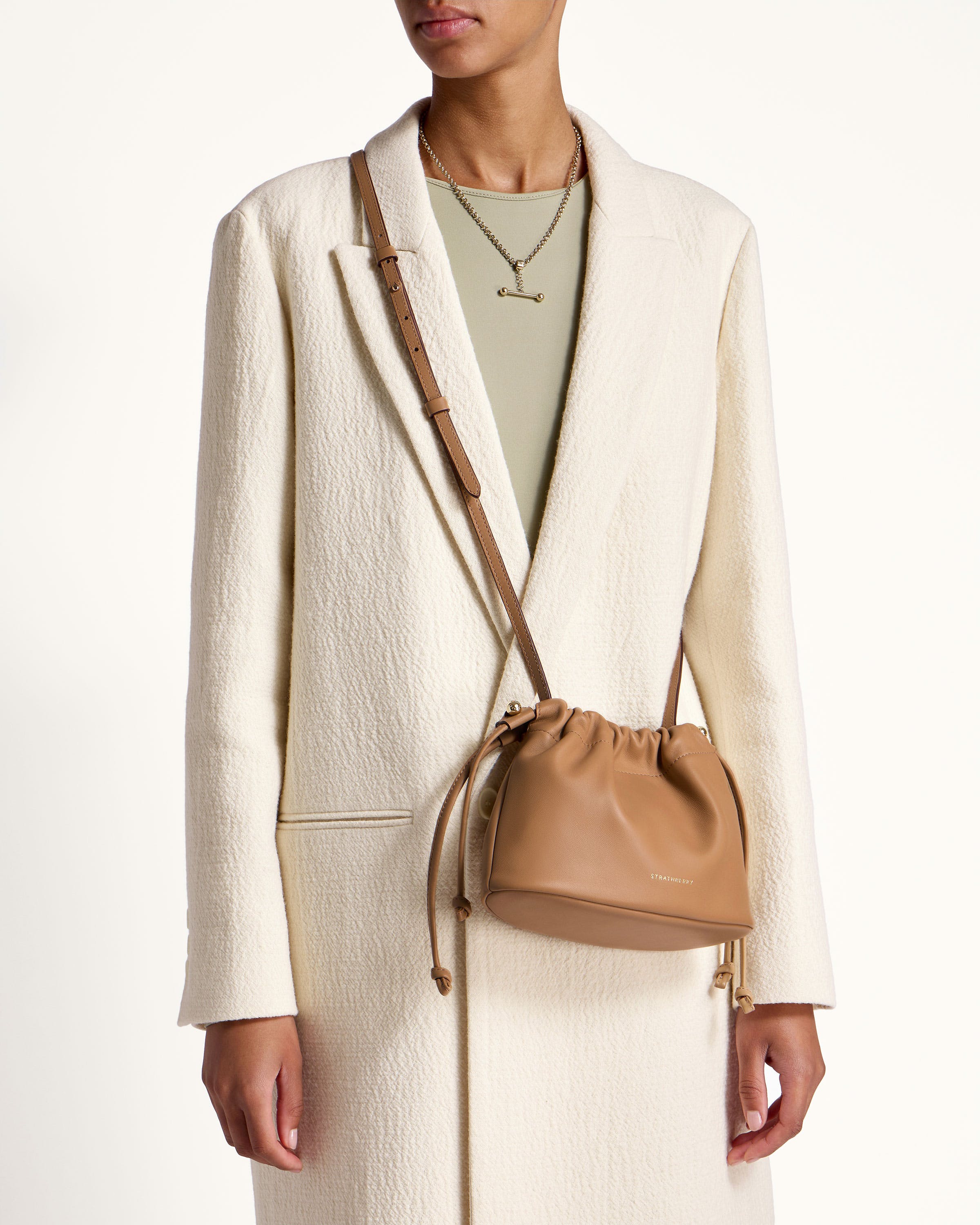 A woman wearing a white coat and a tan purse