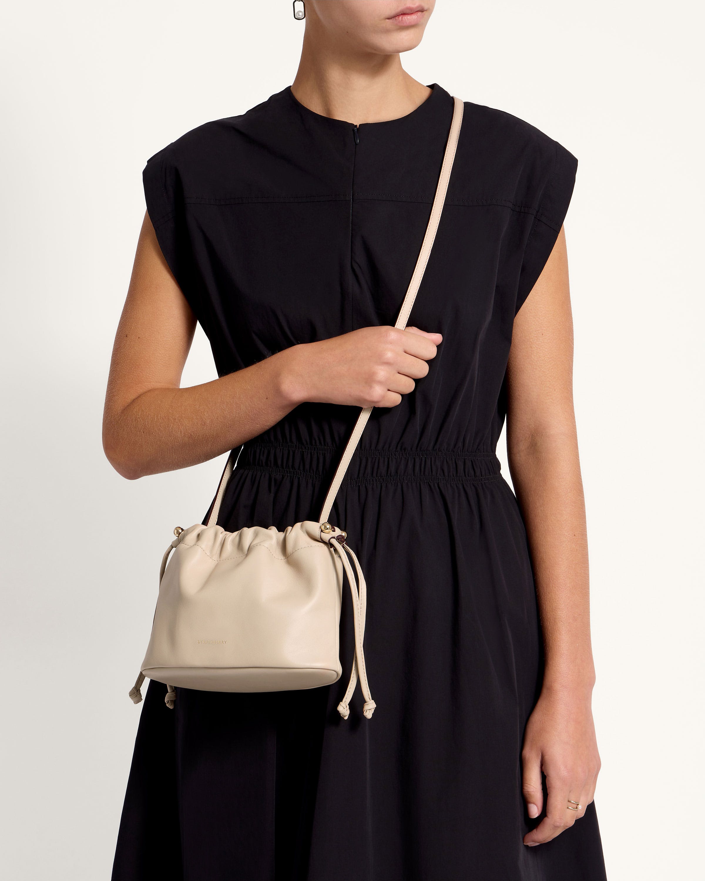 A woman in a black dress holding a white purse