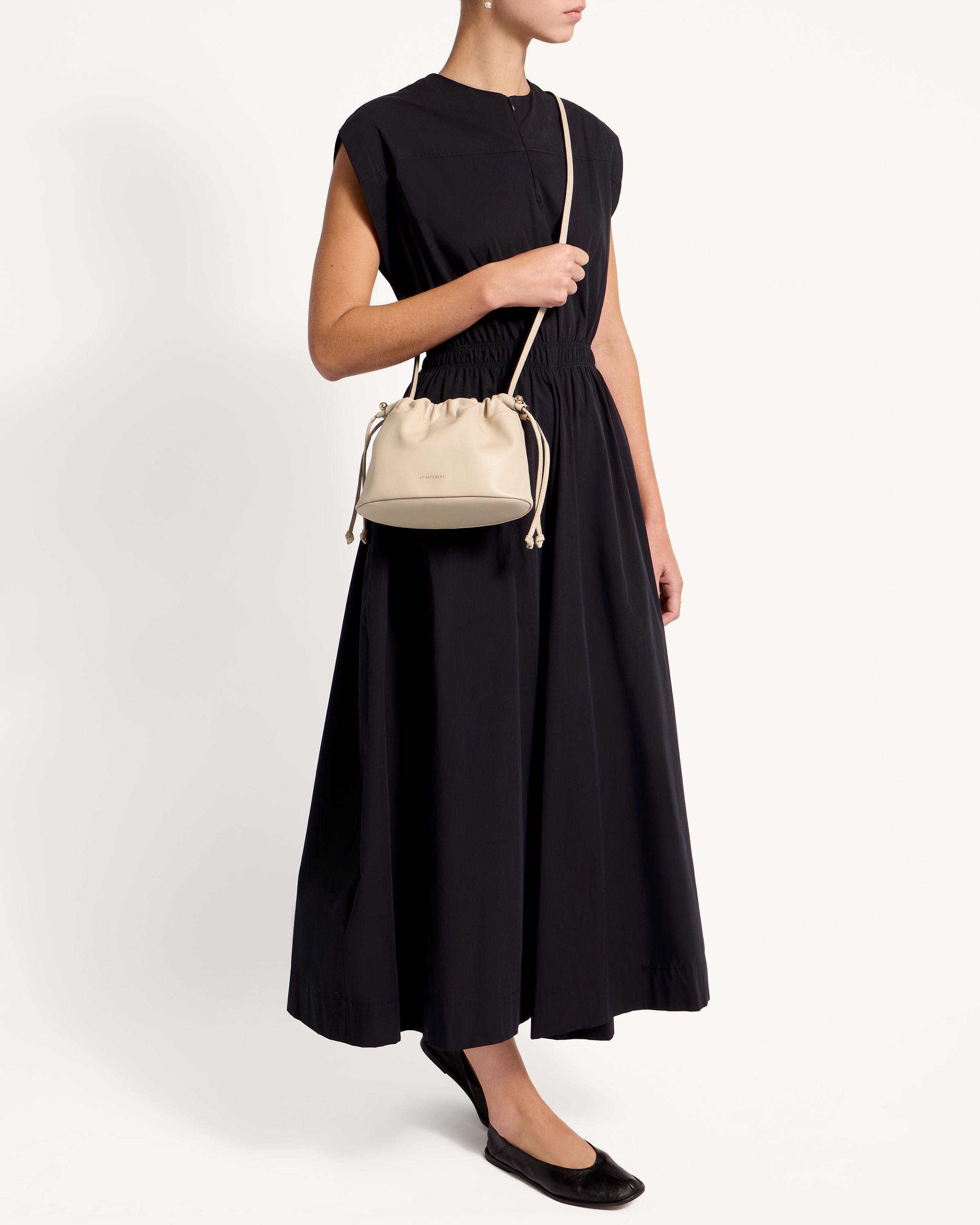 A woman in a black dress holding a white purse