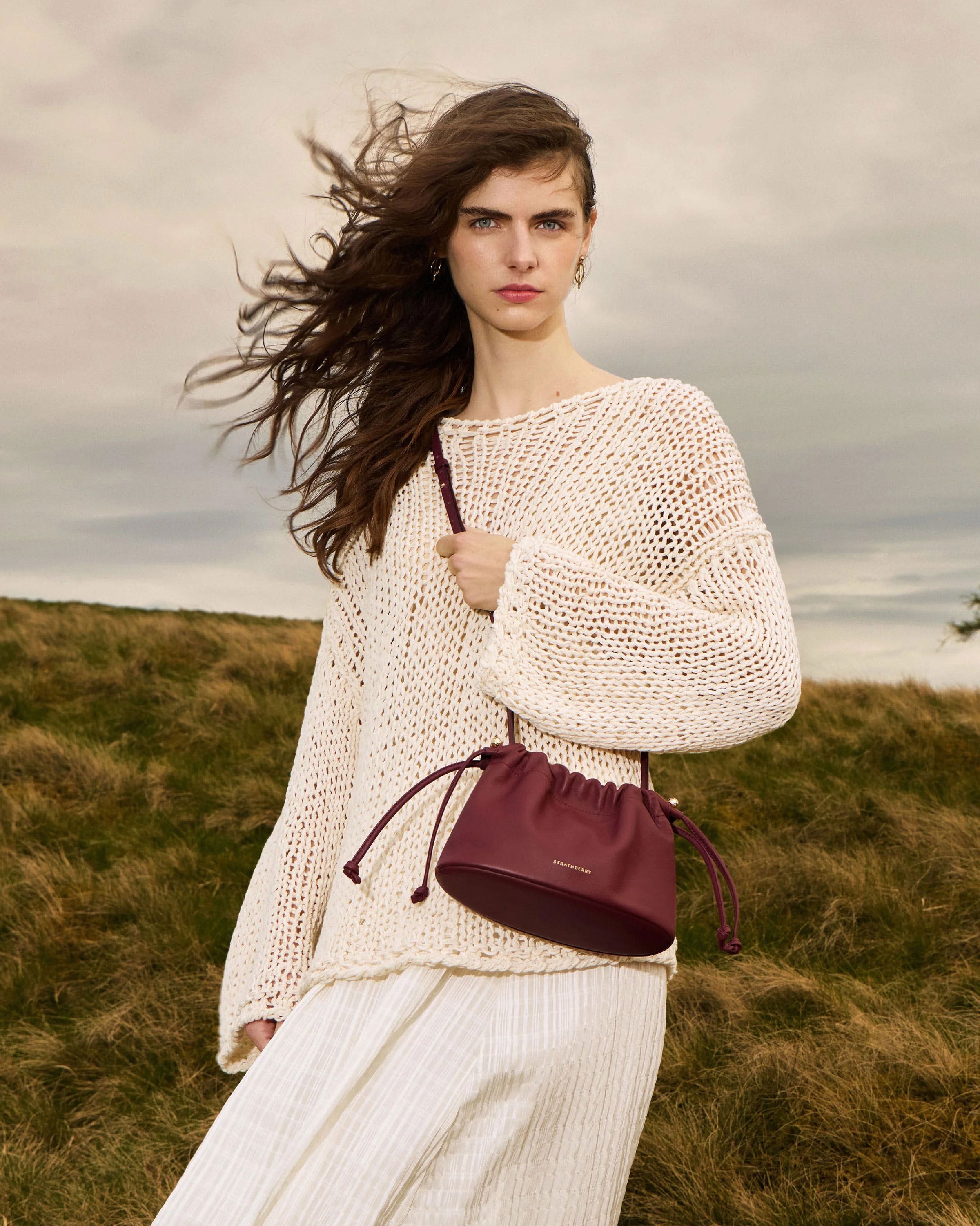 A woman in a white dress carrying a maroon purse