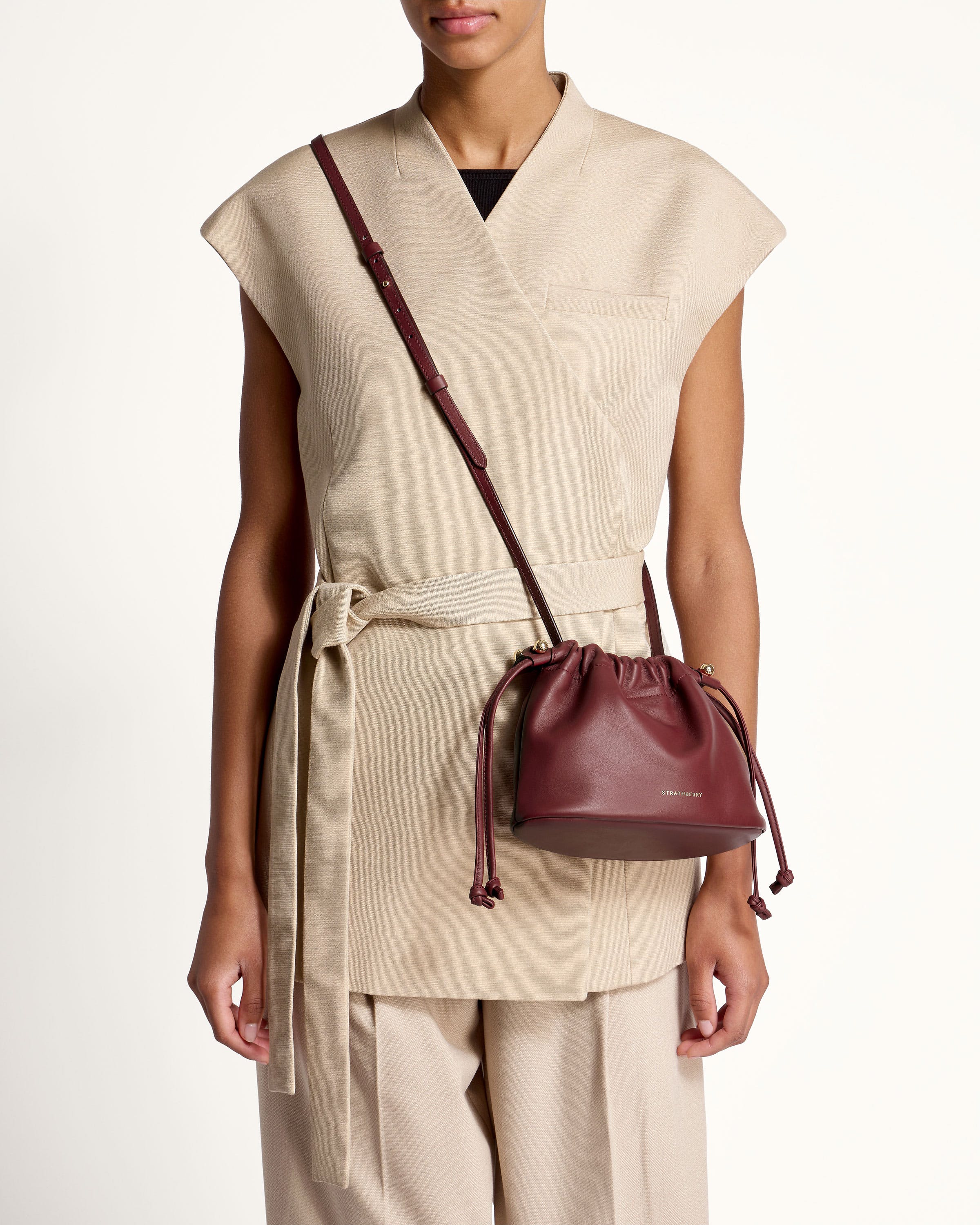 A woman wearing a beige vest and a brown purse