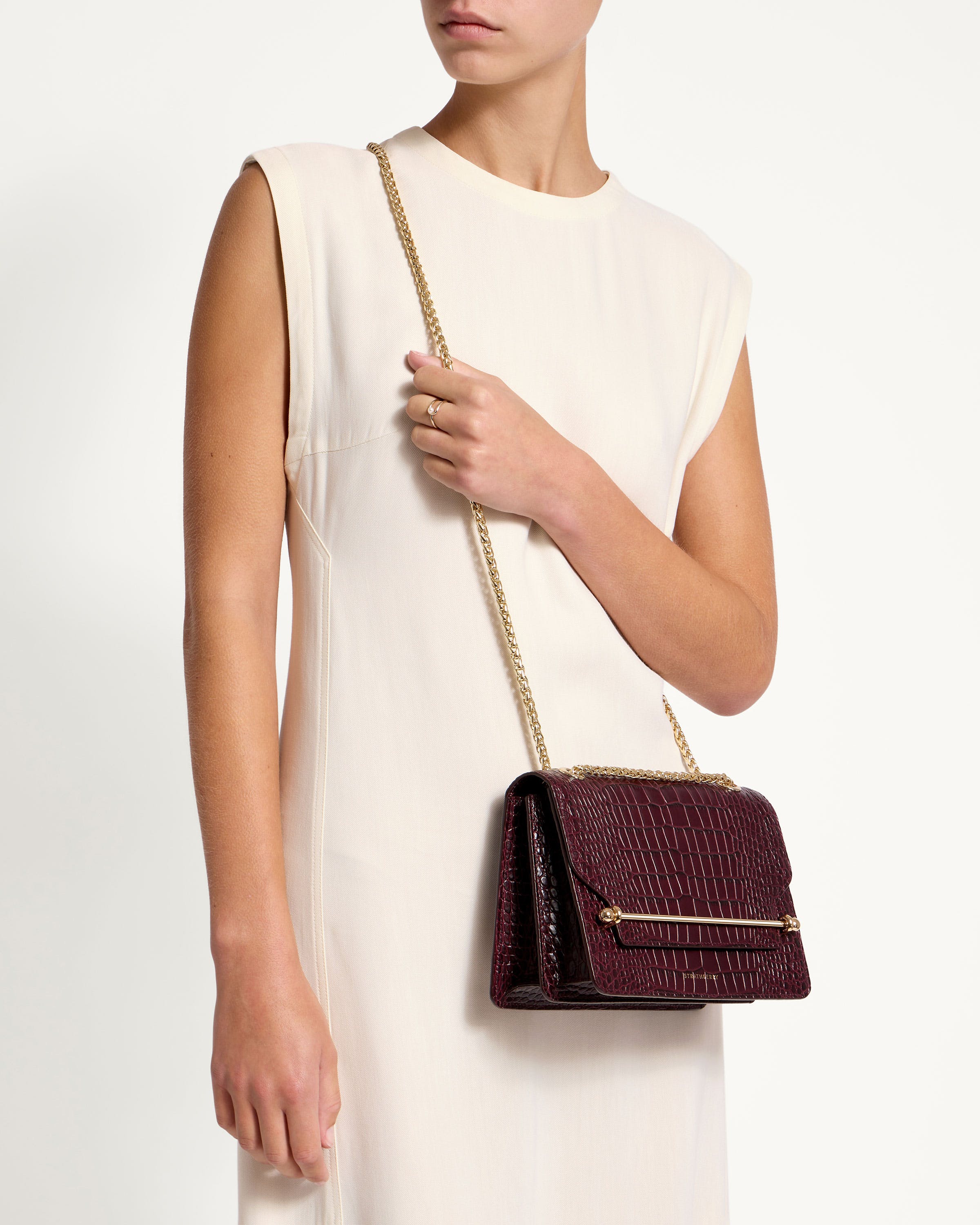 A woman in a white dress holding a burgundy purse