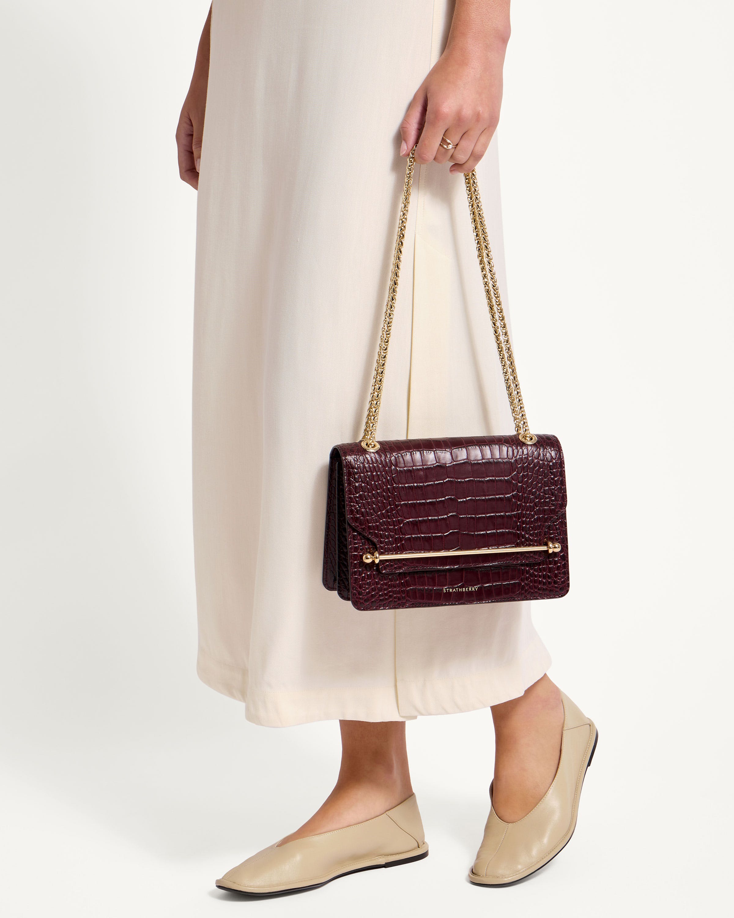 A woman in a white dress holding a brown purse