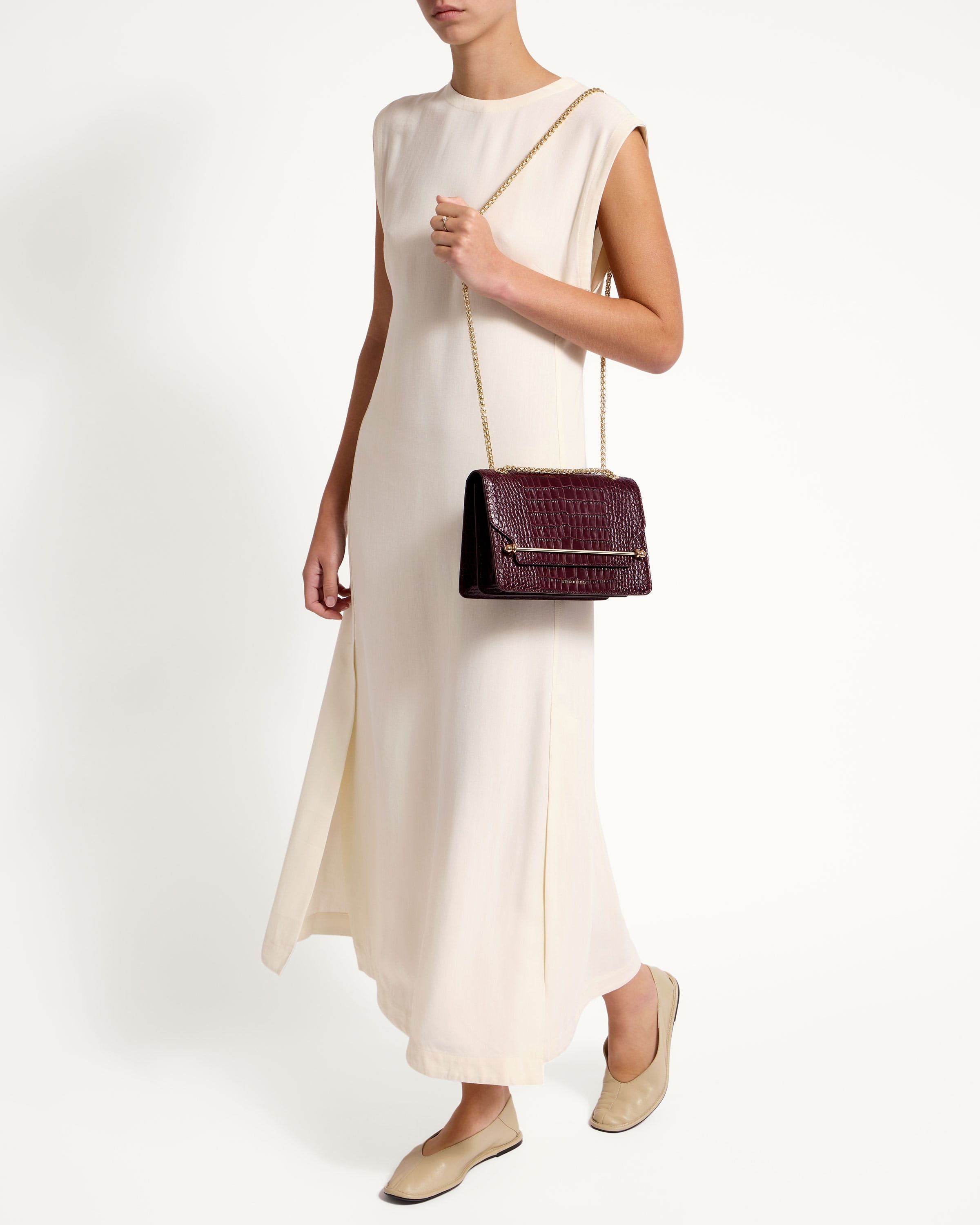 A woman in a white dress holding a brown purse