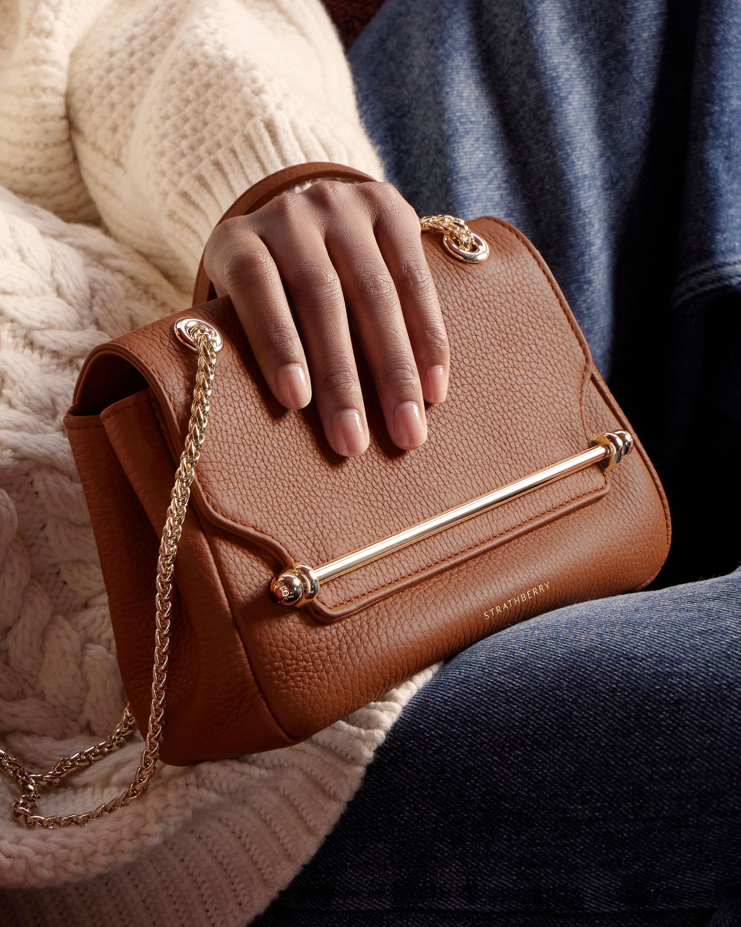 A woman holding a brown purse on her lap