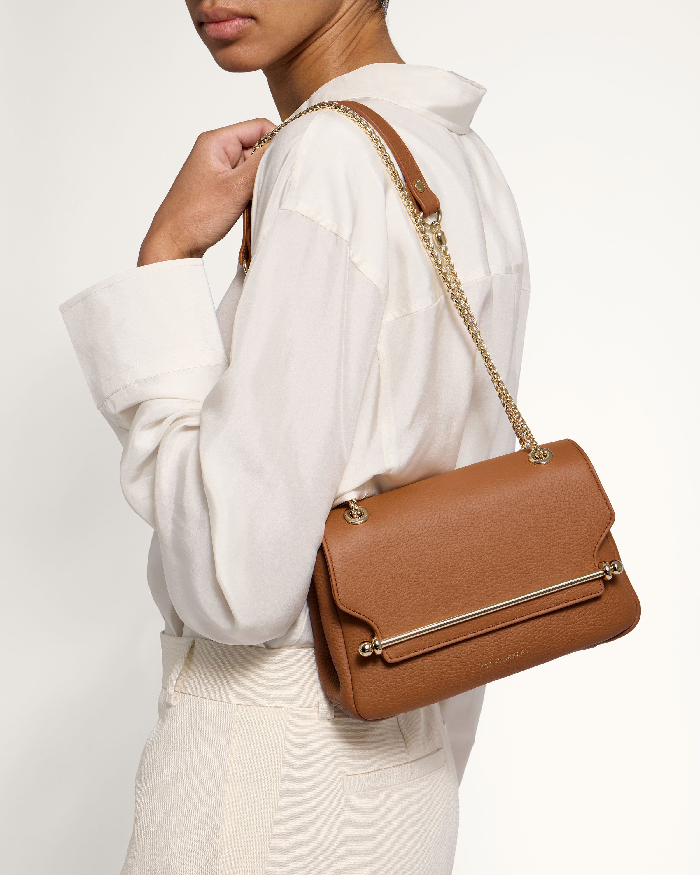 A woman in a white shirt holding a brown purse