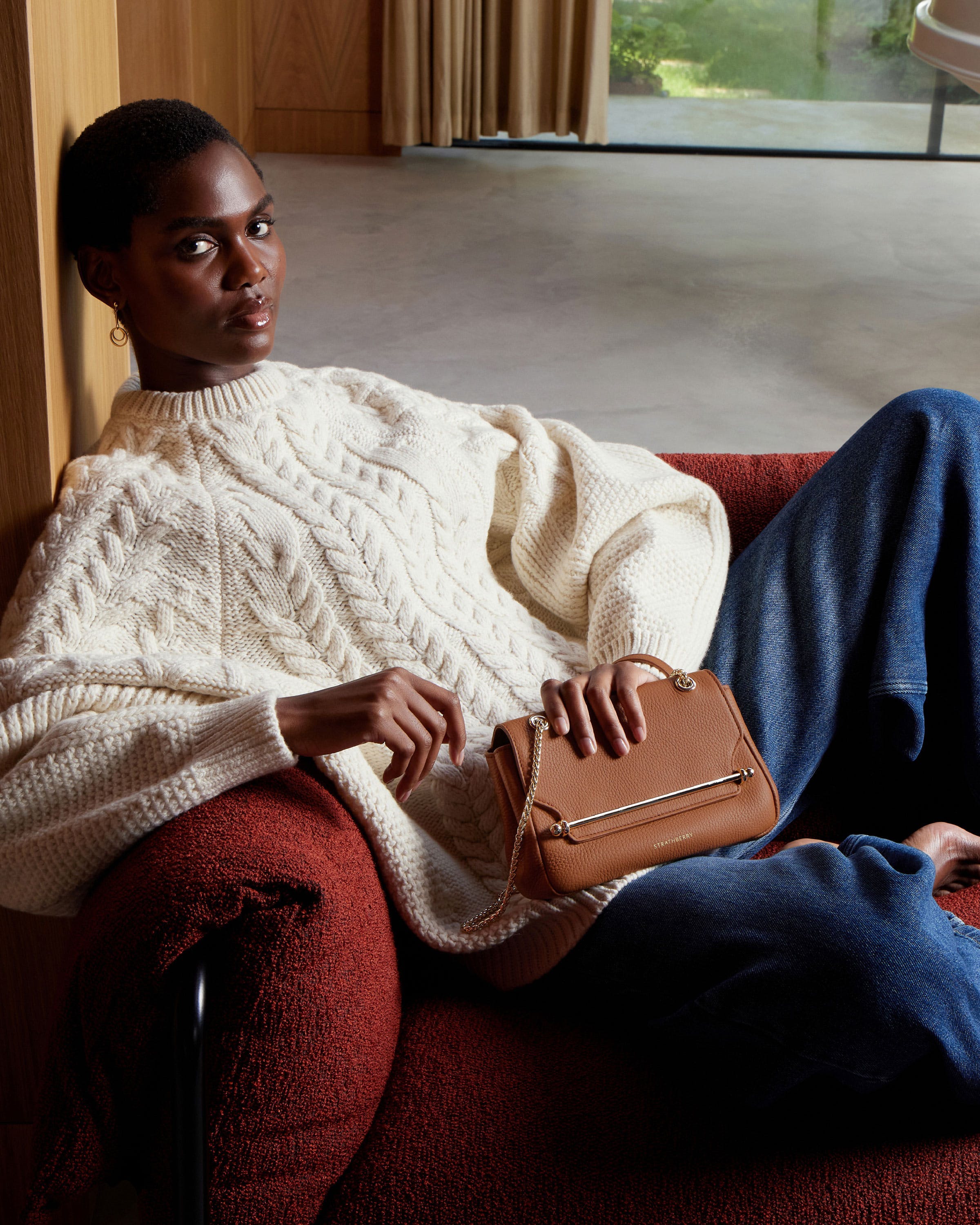 A woman sitting on a couch holding a purse