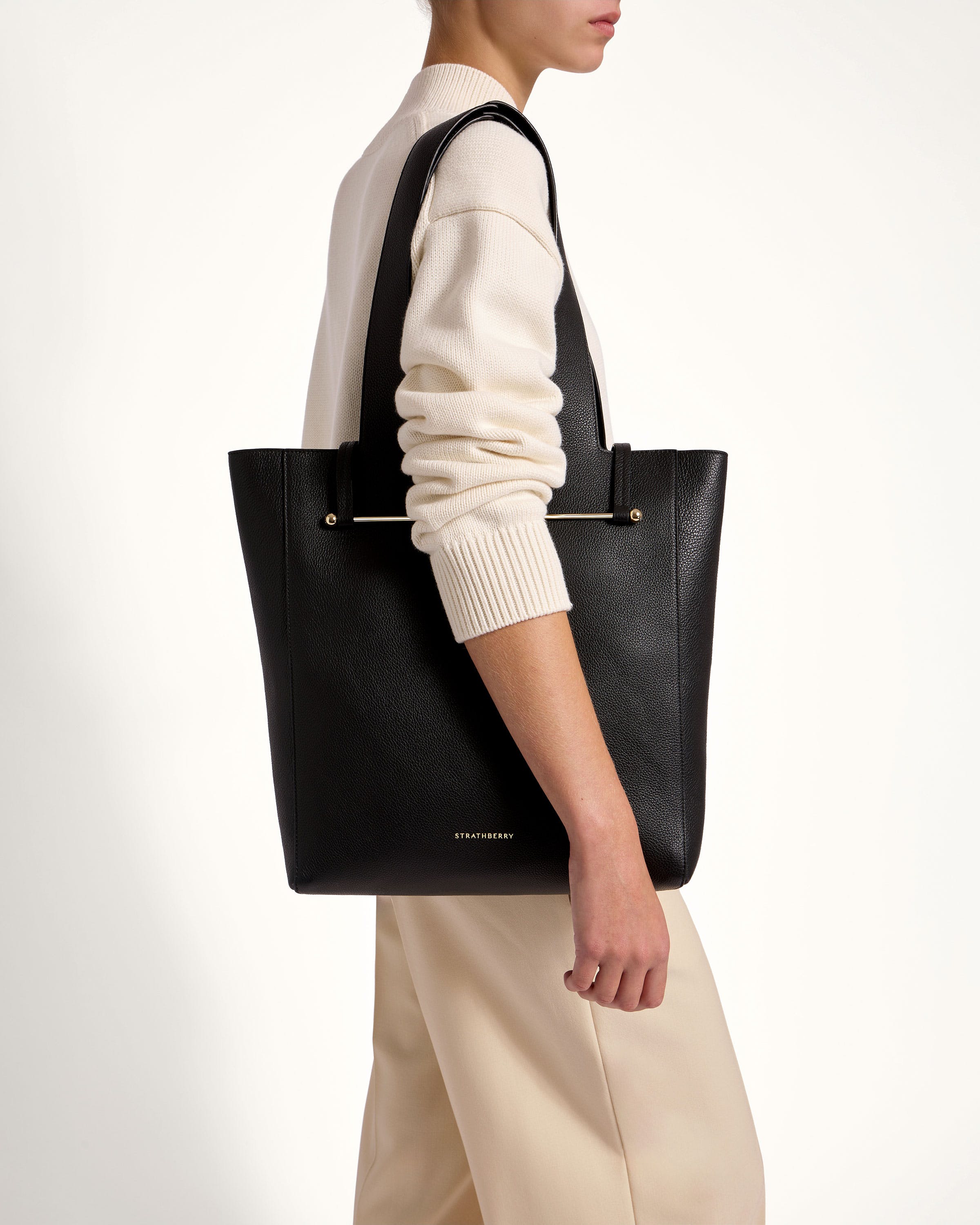 A woman carrying a black tote bag