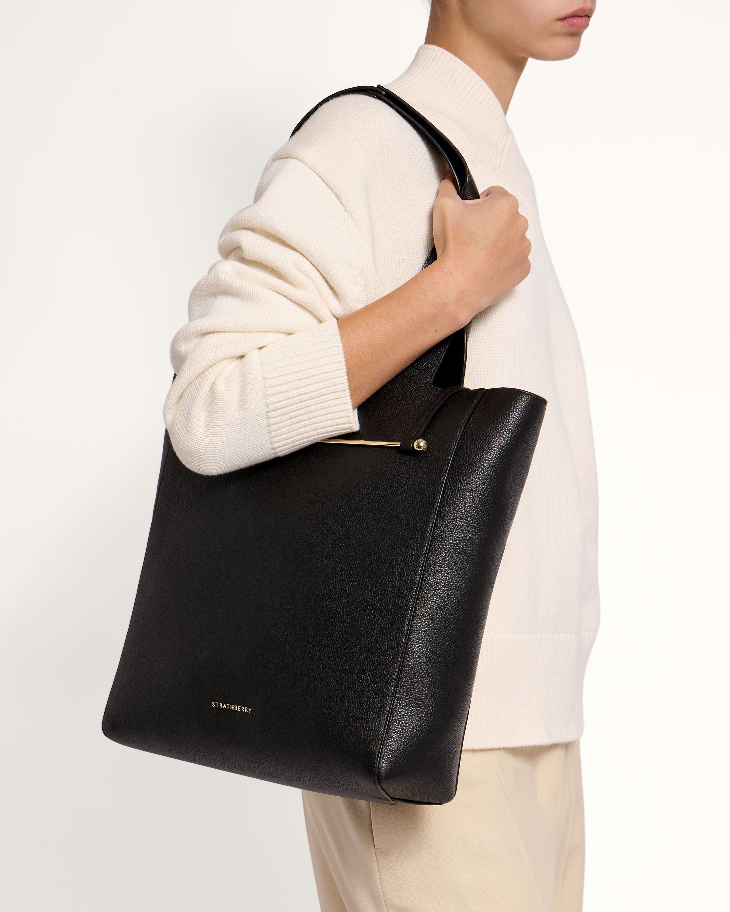 A woman carrying a black leather tote bag