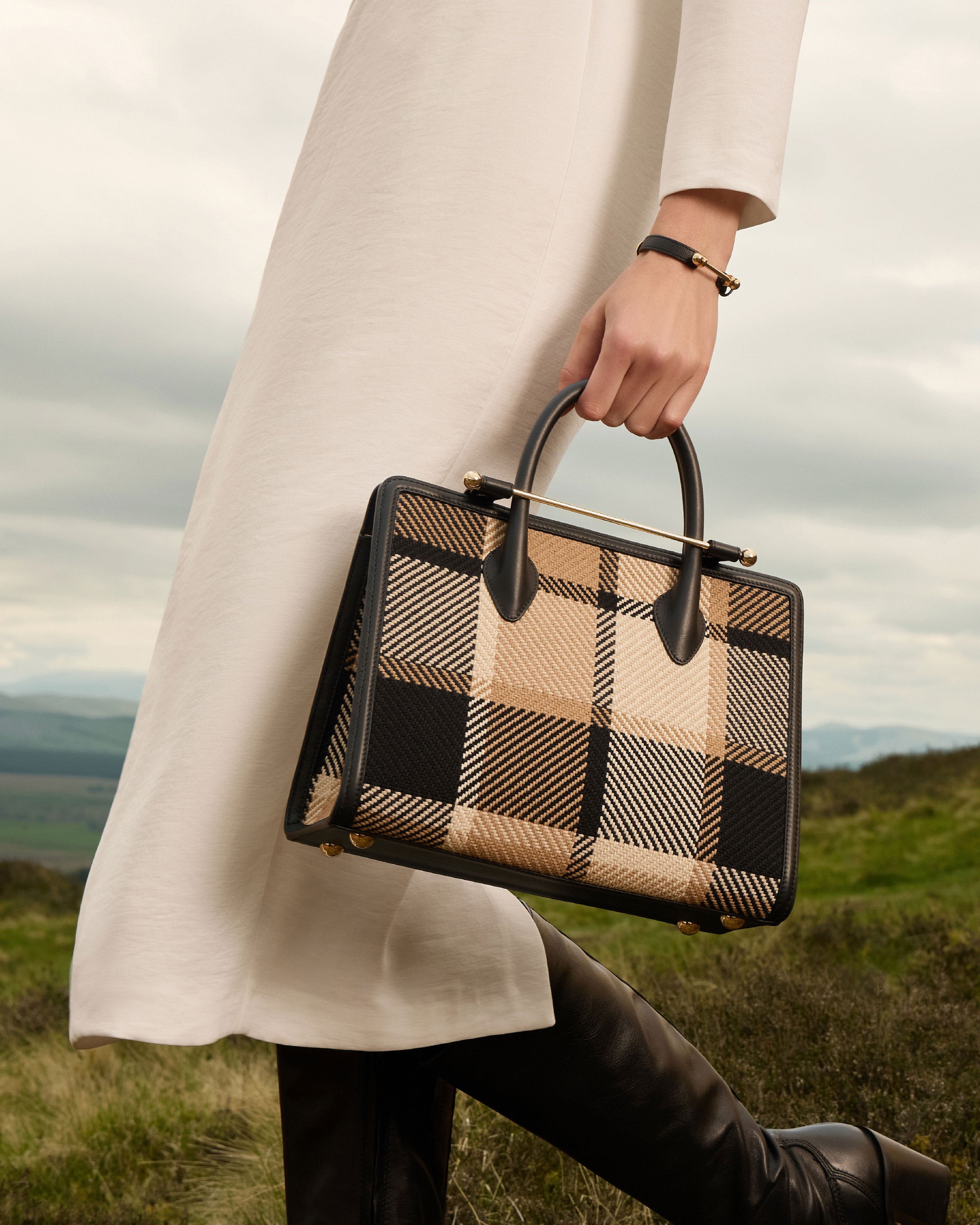 A woman in a white dress carrying a black and tan purse