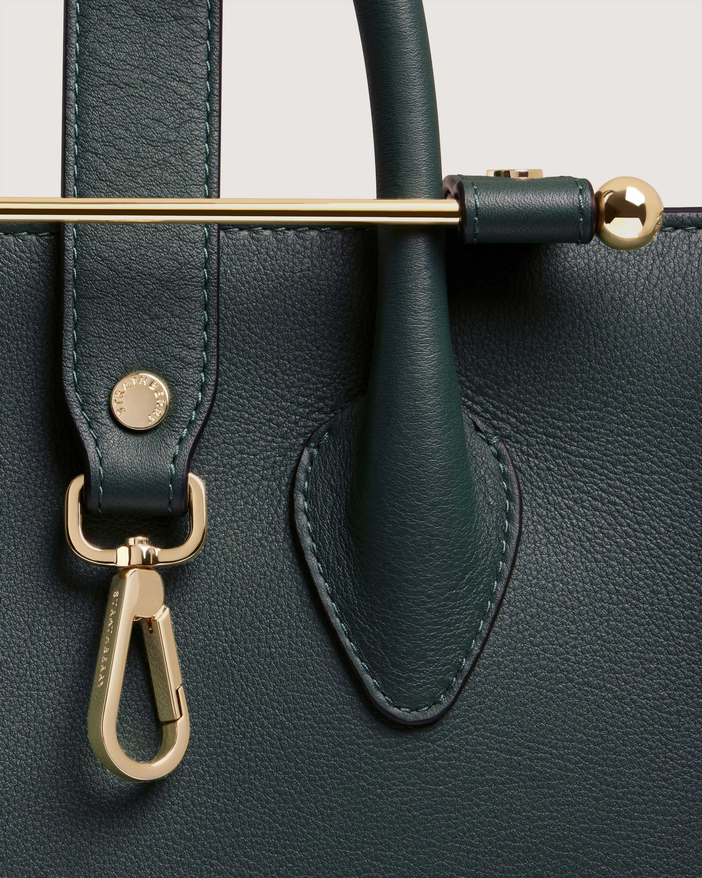 A close up of a green purse with a gold handle