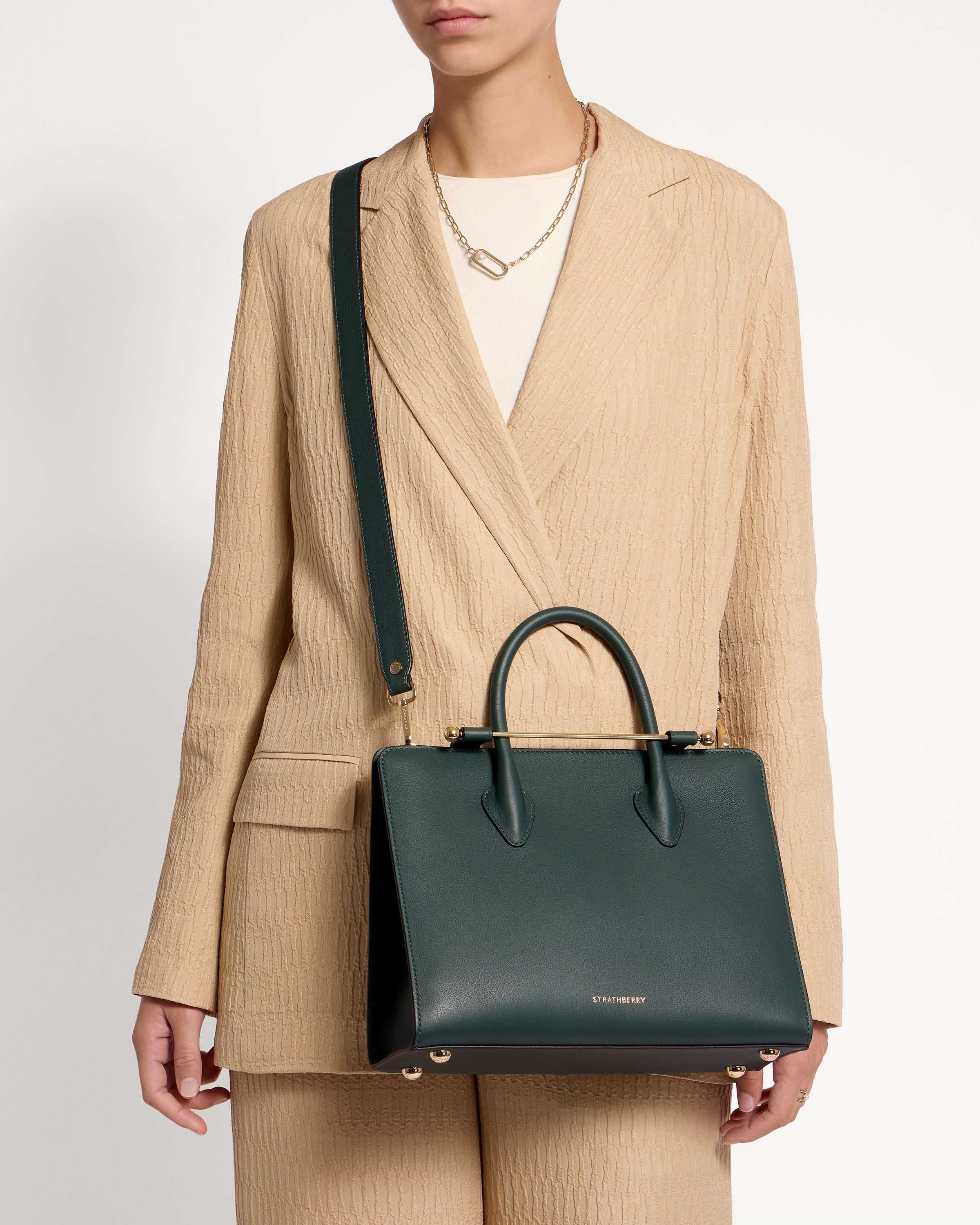 A woman is holding a green handbag