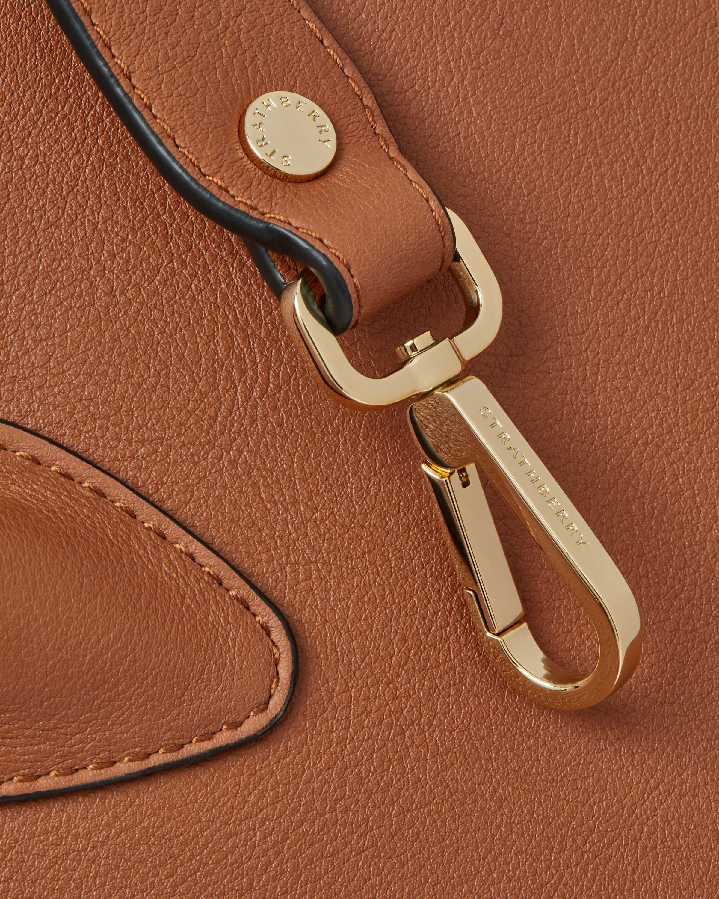 A close up of a brown purse with a gold handle