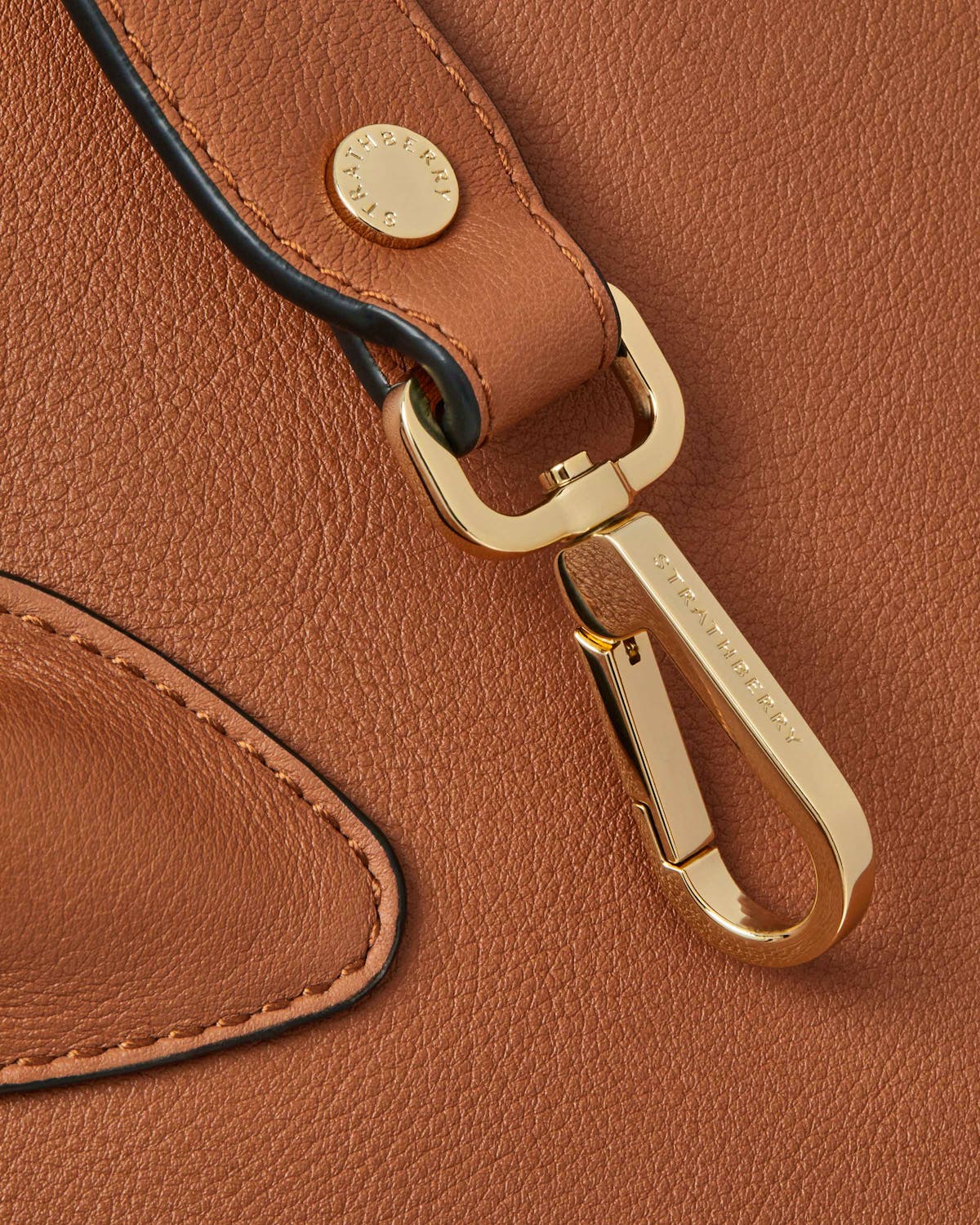 Chestnut Strathberry midi tote close-up of gold clip and grained leather