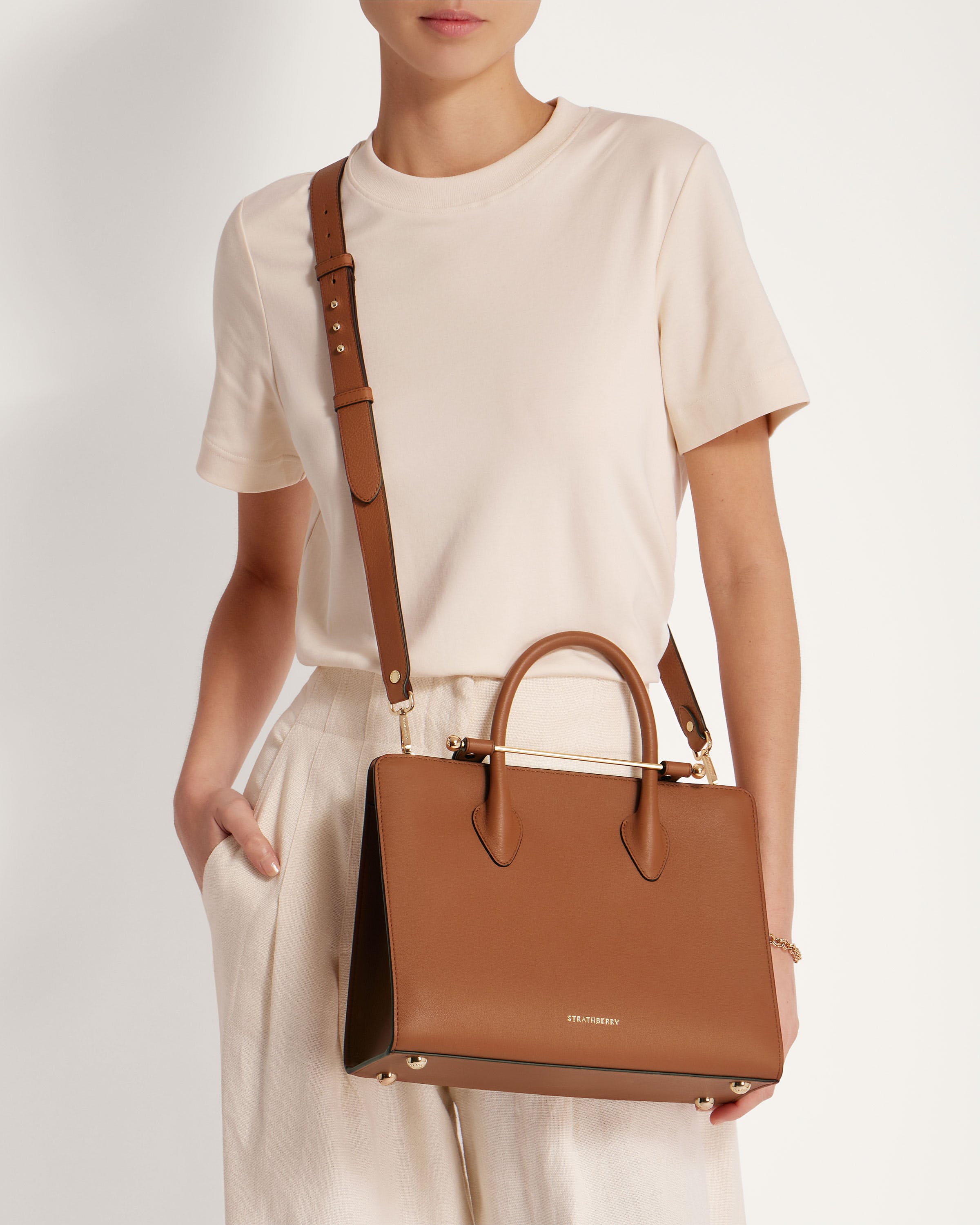 A woman is holding a brown handbag