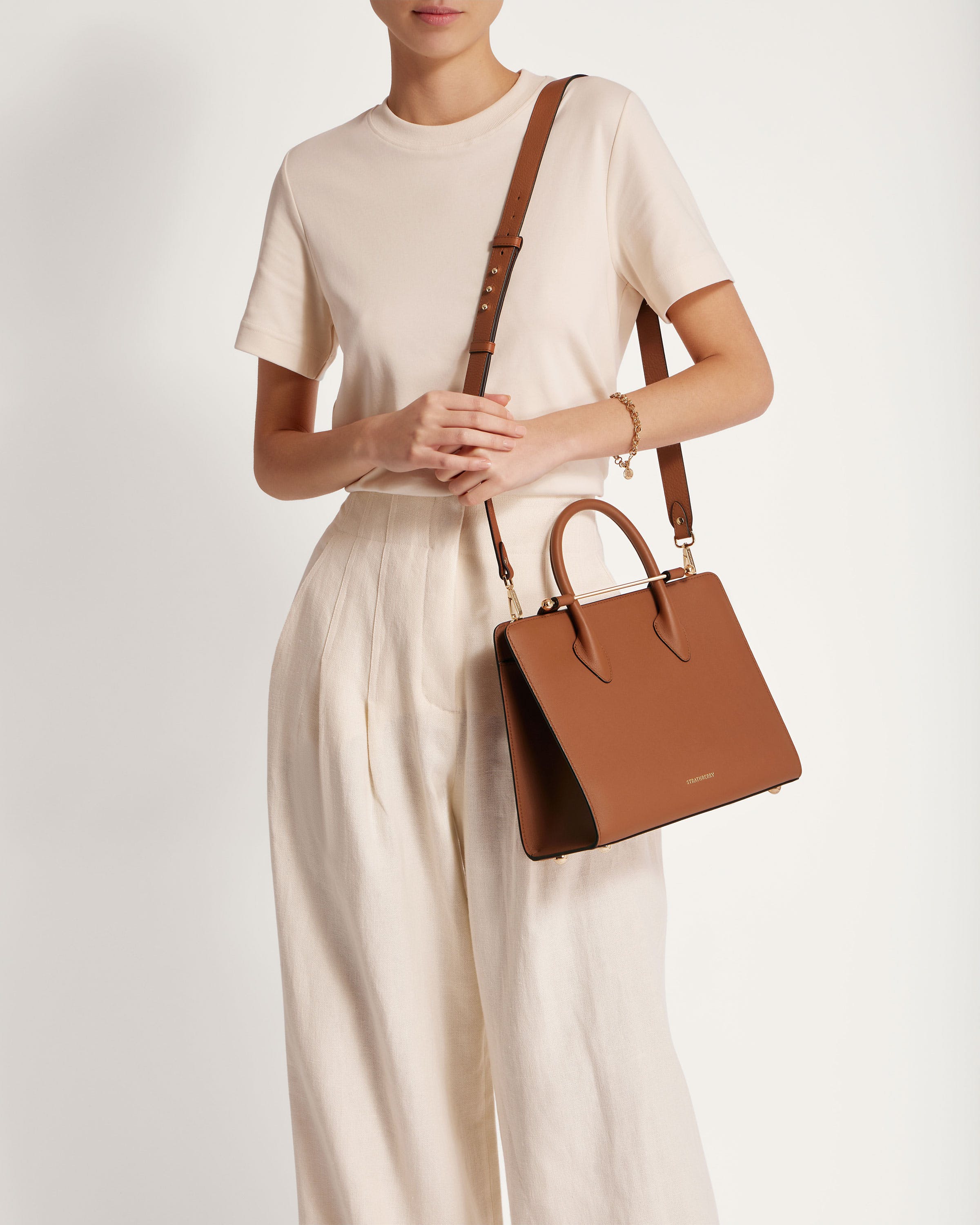 A woman is holding a brown handbag