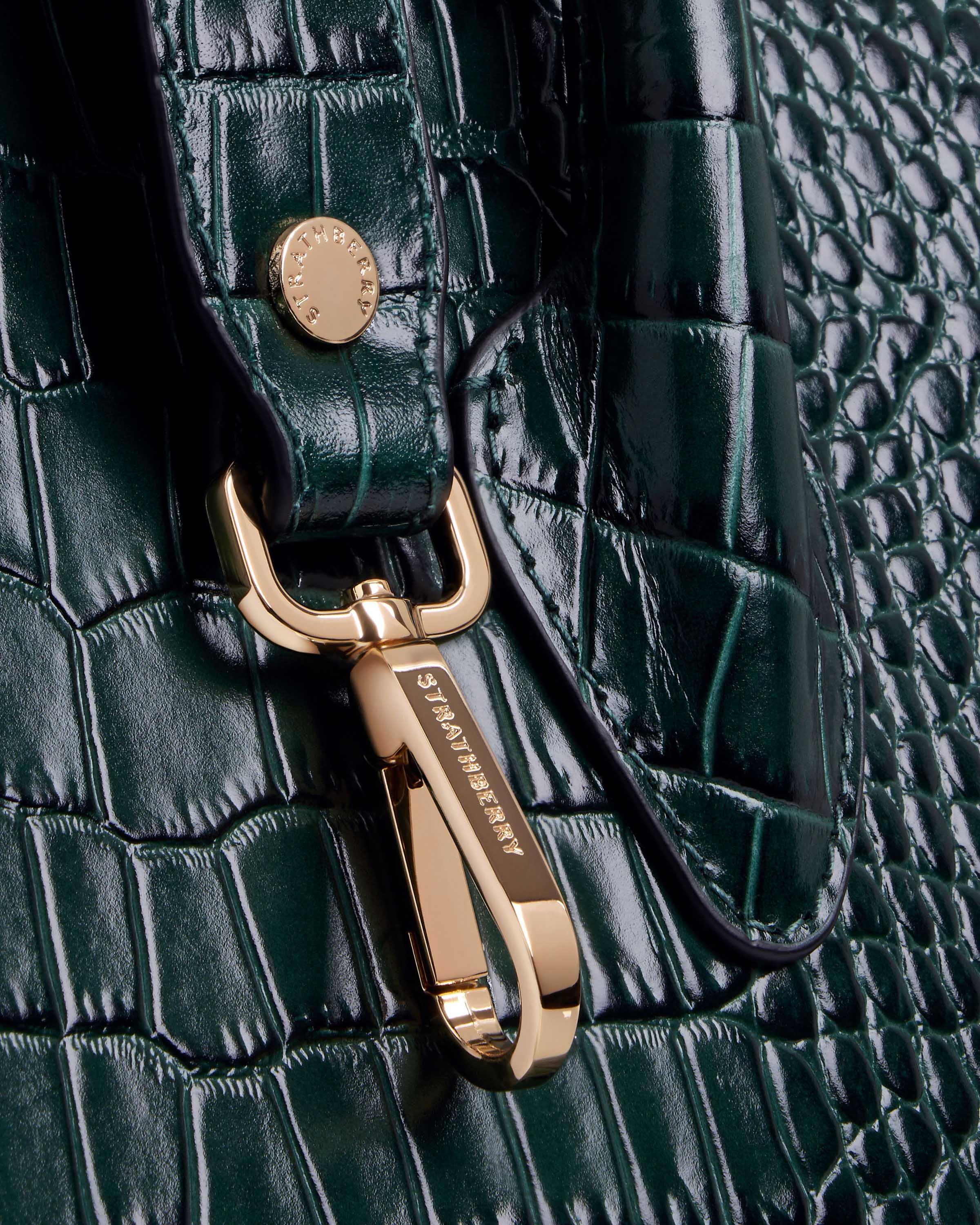 A close up of a green alligator skin purse