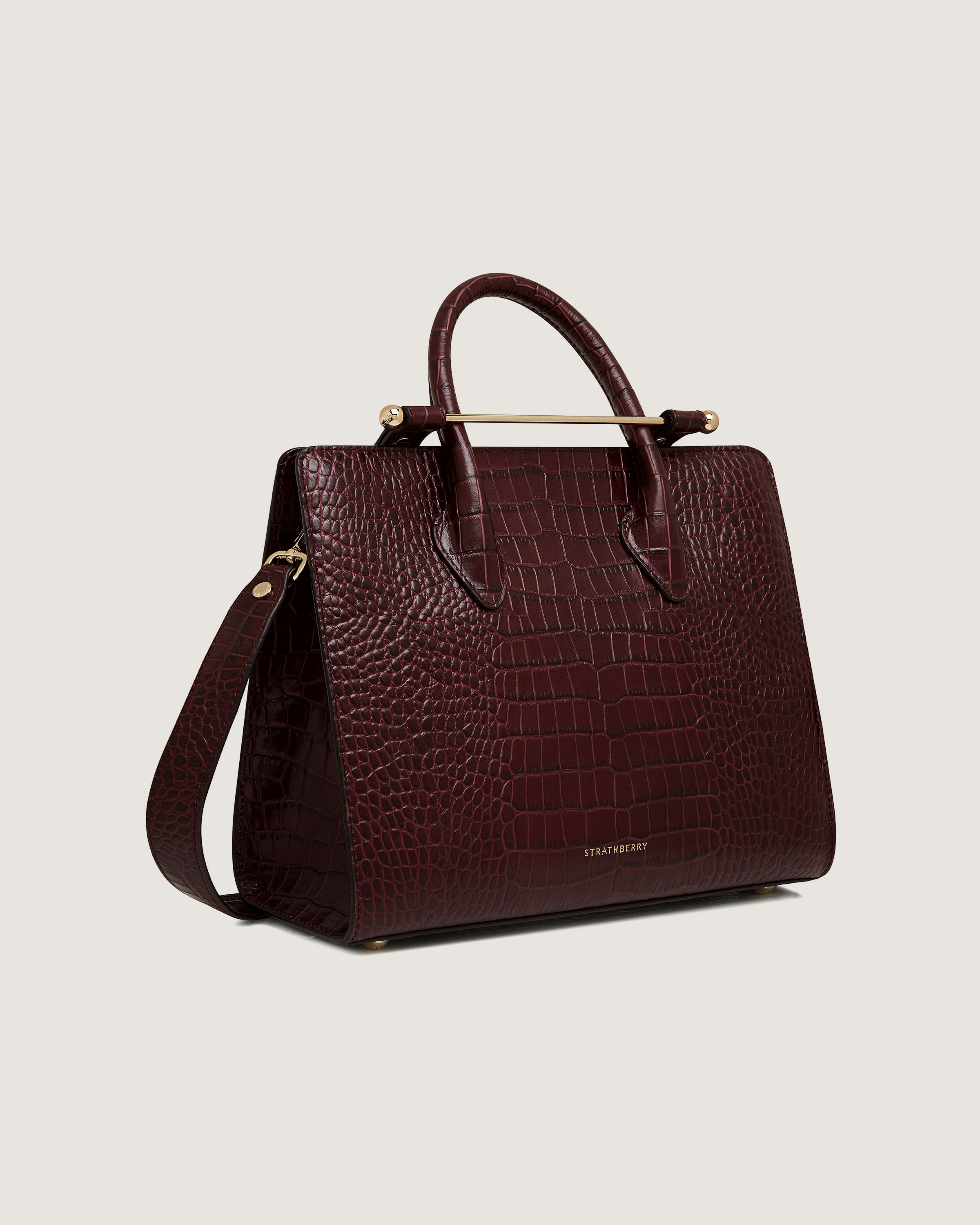 A maroon handbag with a gold handle