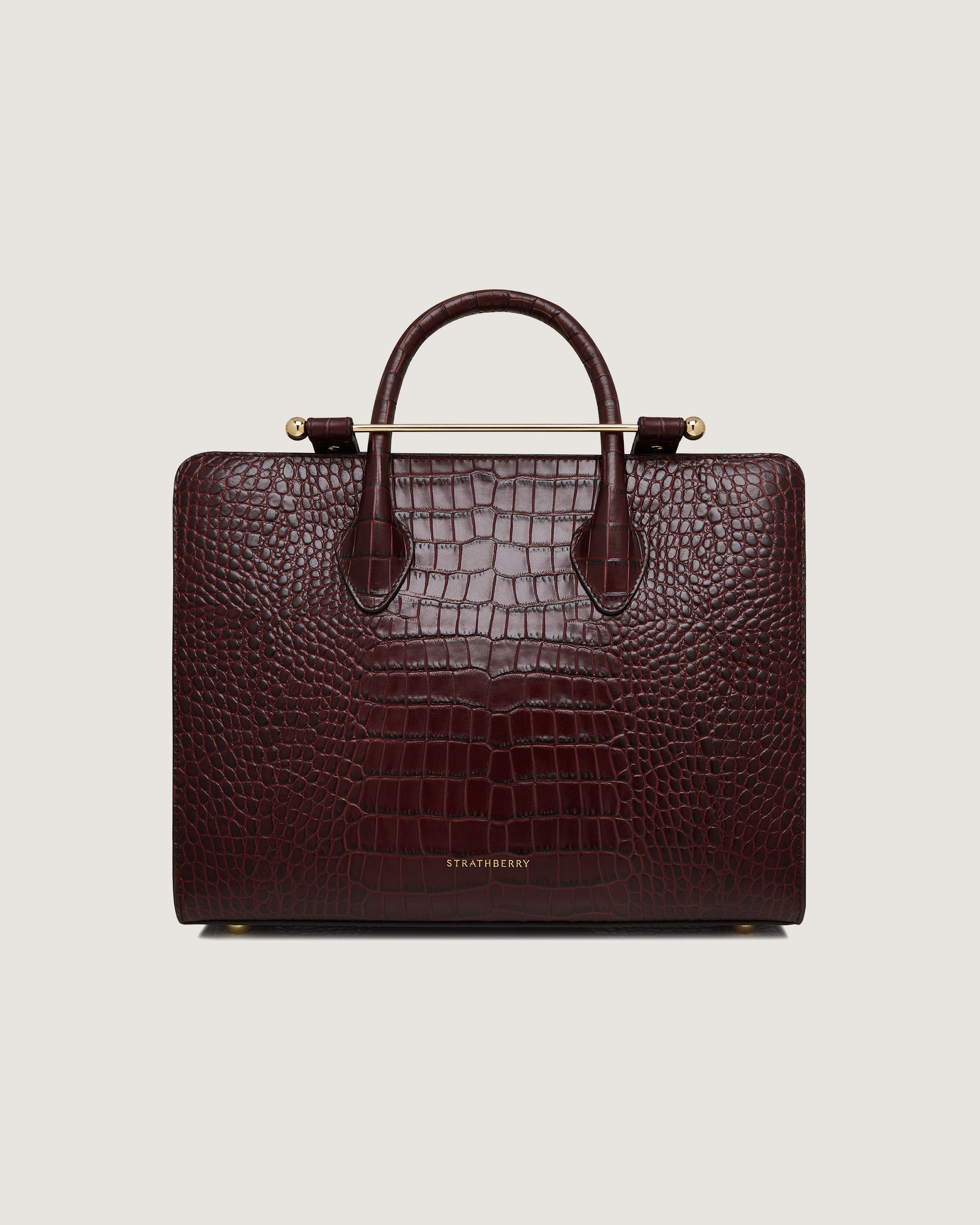 A brown alligator skin briefcase with a gold handle