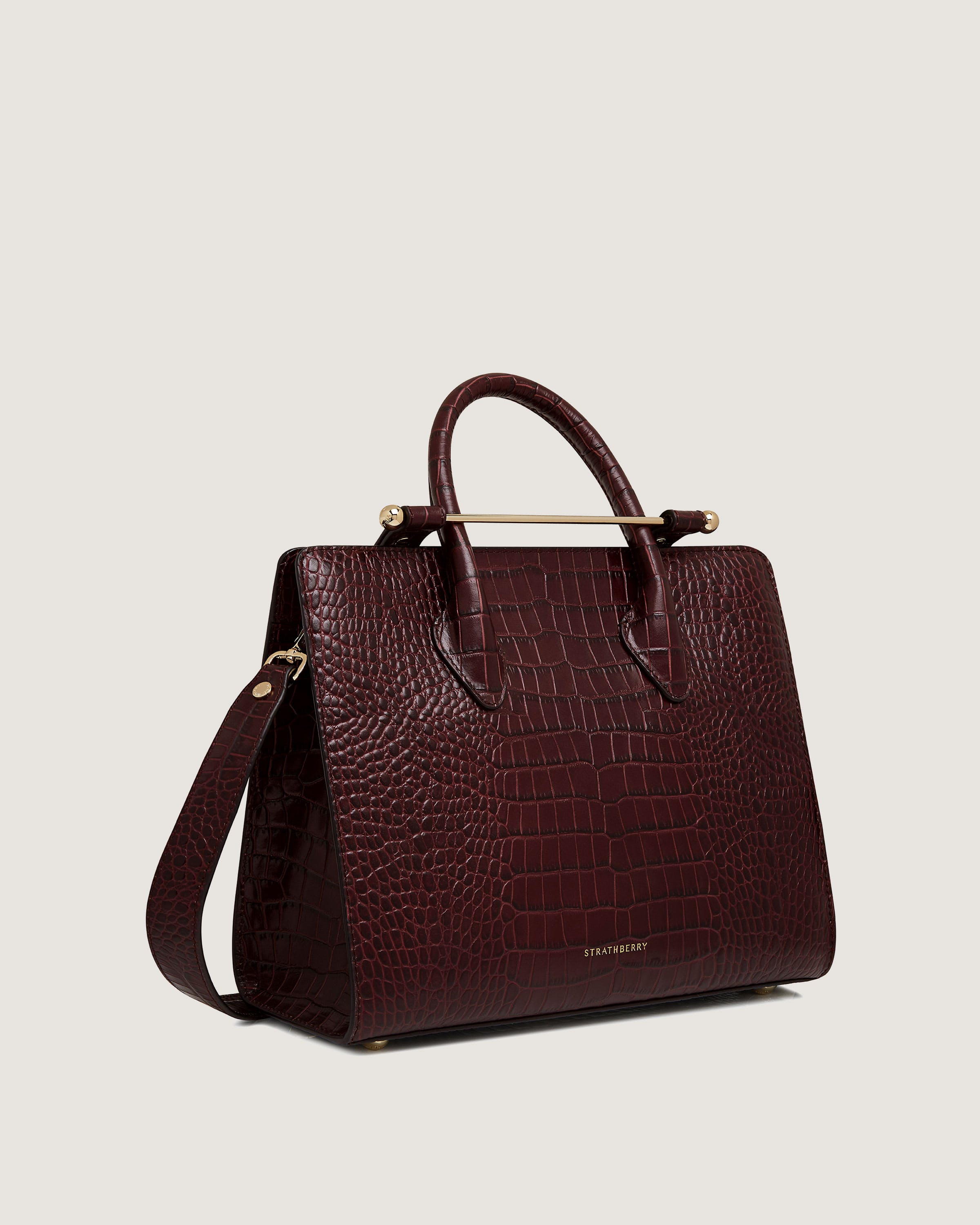 A maroon handbag with a gold handle