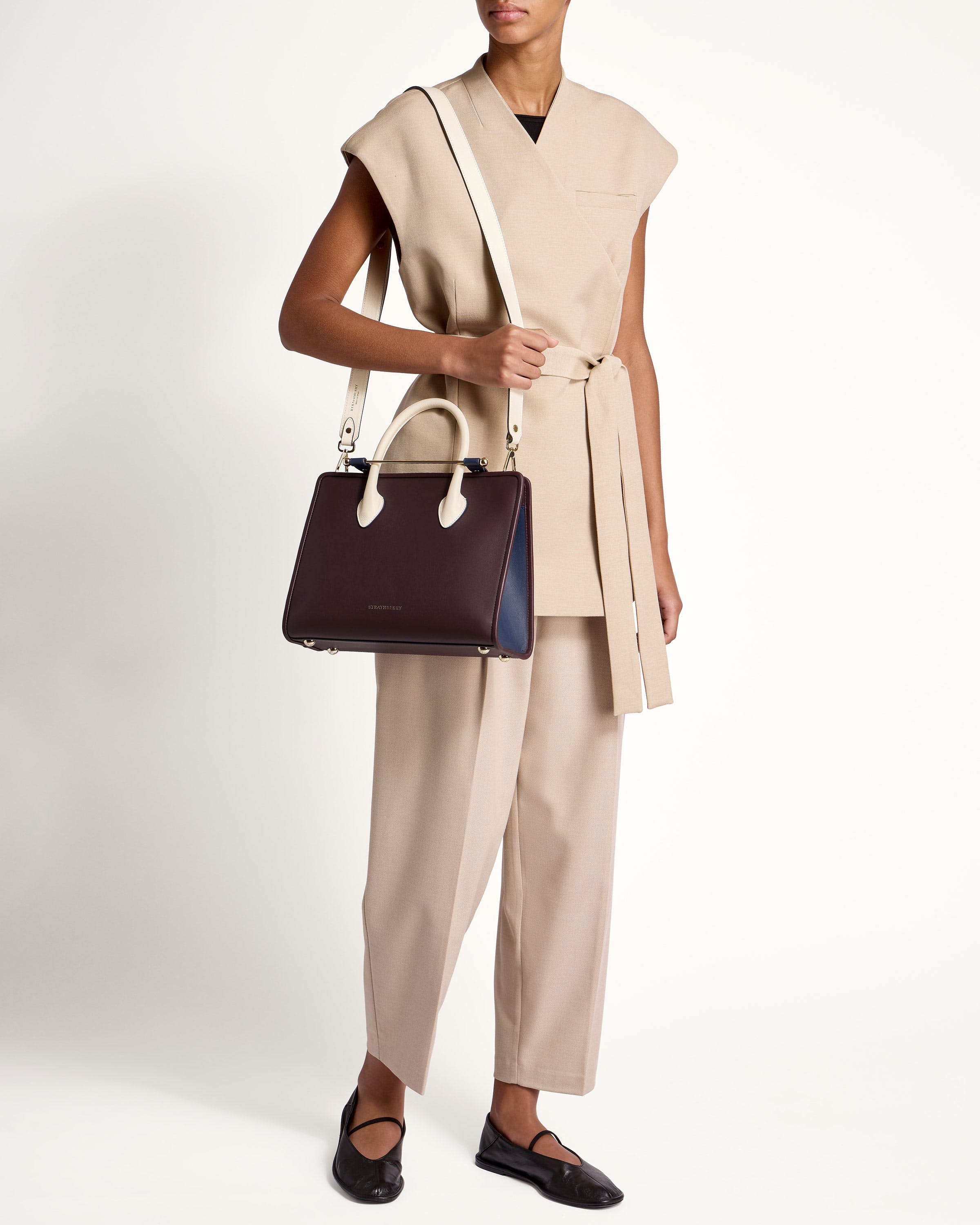 A woman holding a brown and black handbag